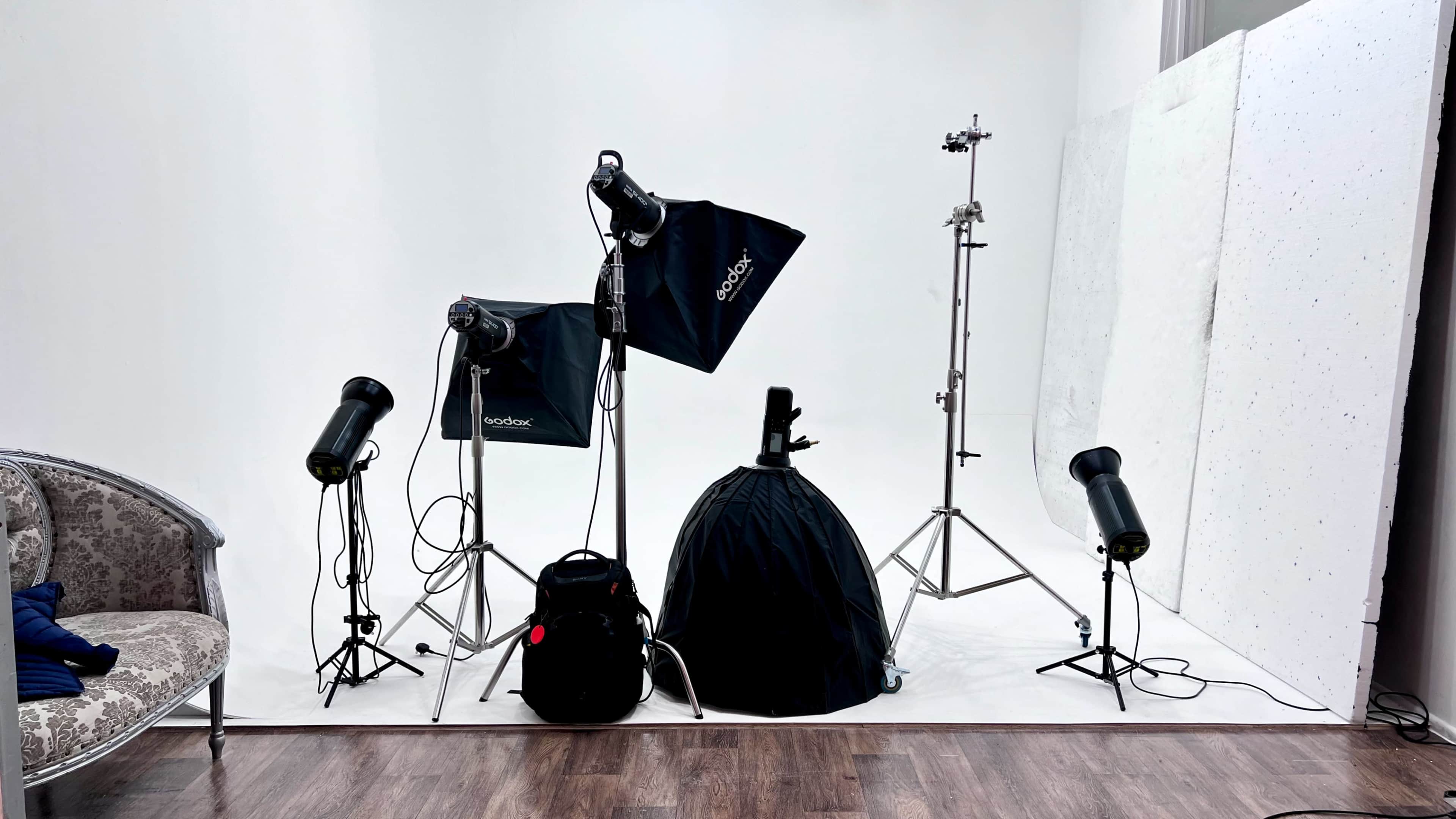 A photography studio setup with various lighting equipment and backdrops arranged in a corner.