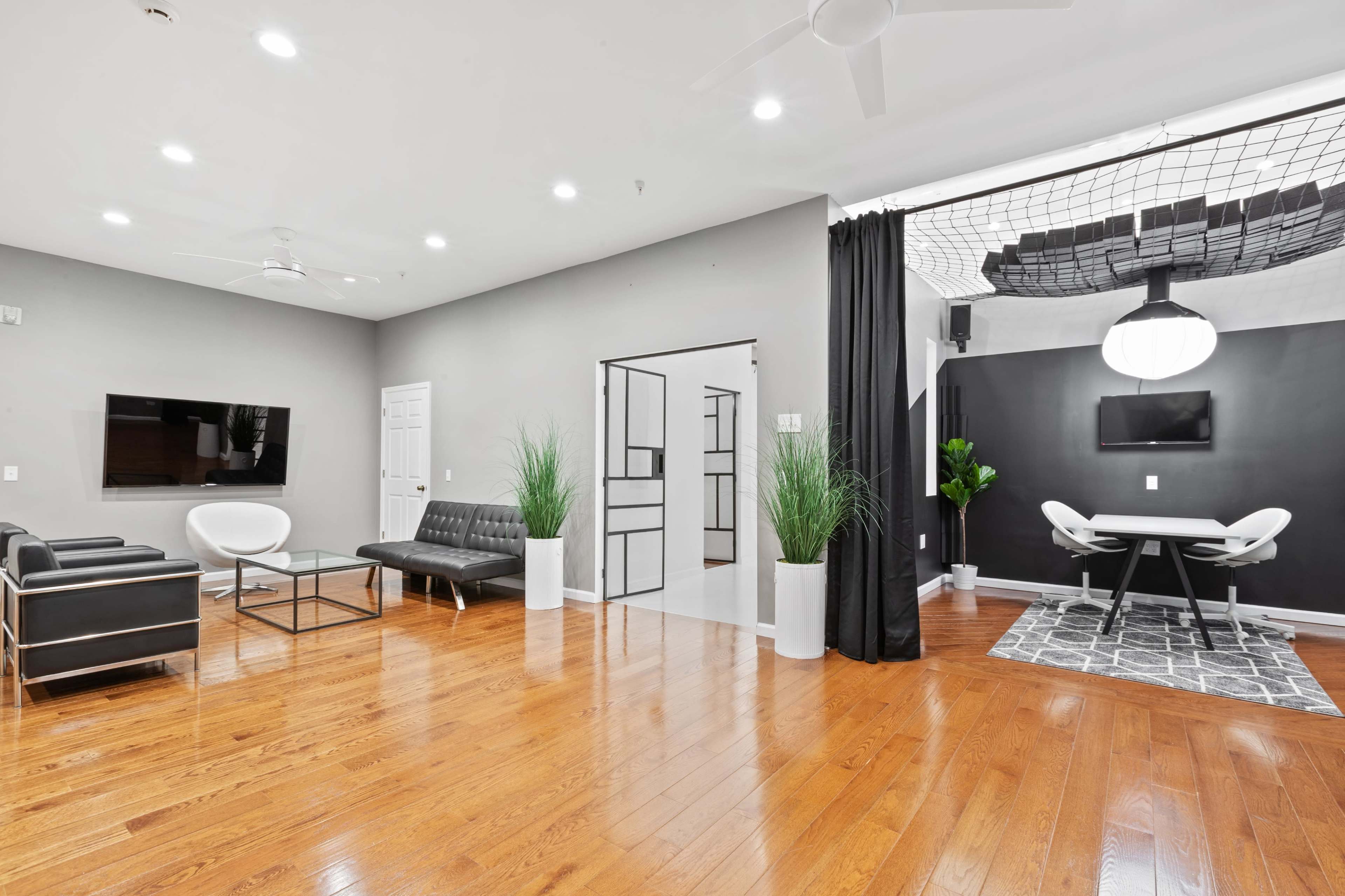 The room features a modern living area with sleek furniture, light wood flooring, and a dining space separated by a partition.