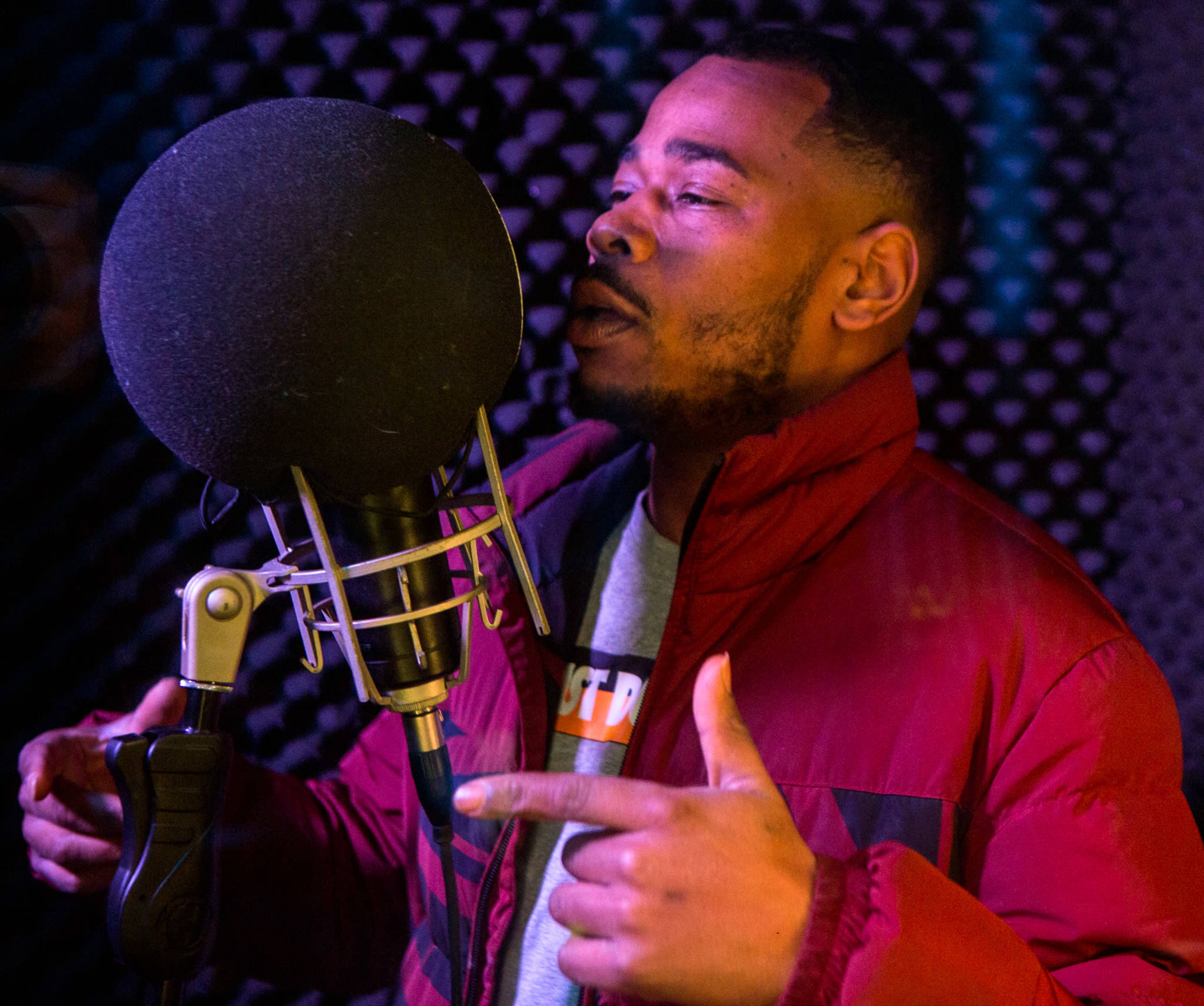 A musician is rapping into a microphone in a recording studio.