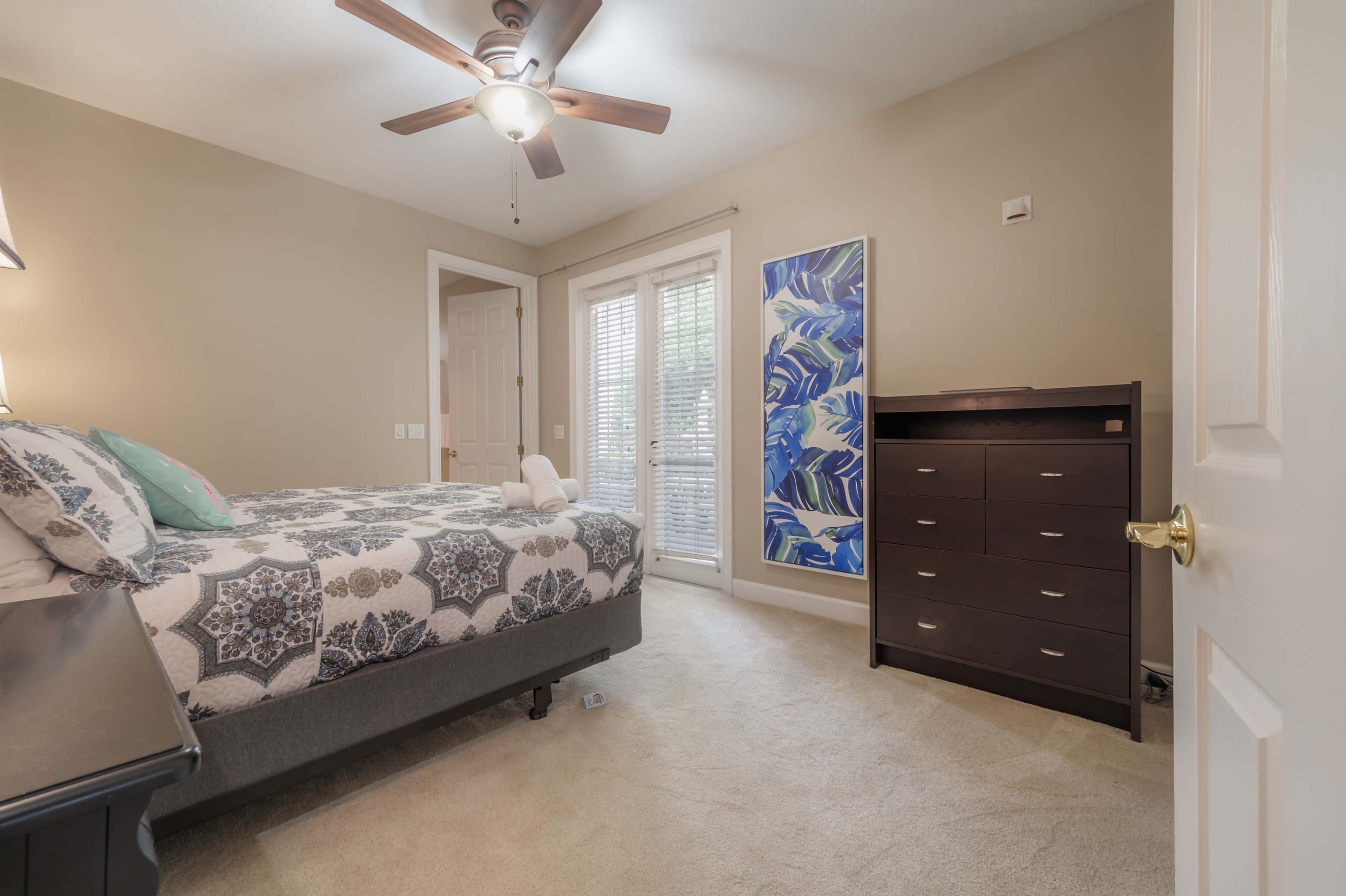 A bedroom with a bed, a dresser, and a set of French doors leading to an exterior space.