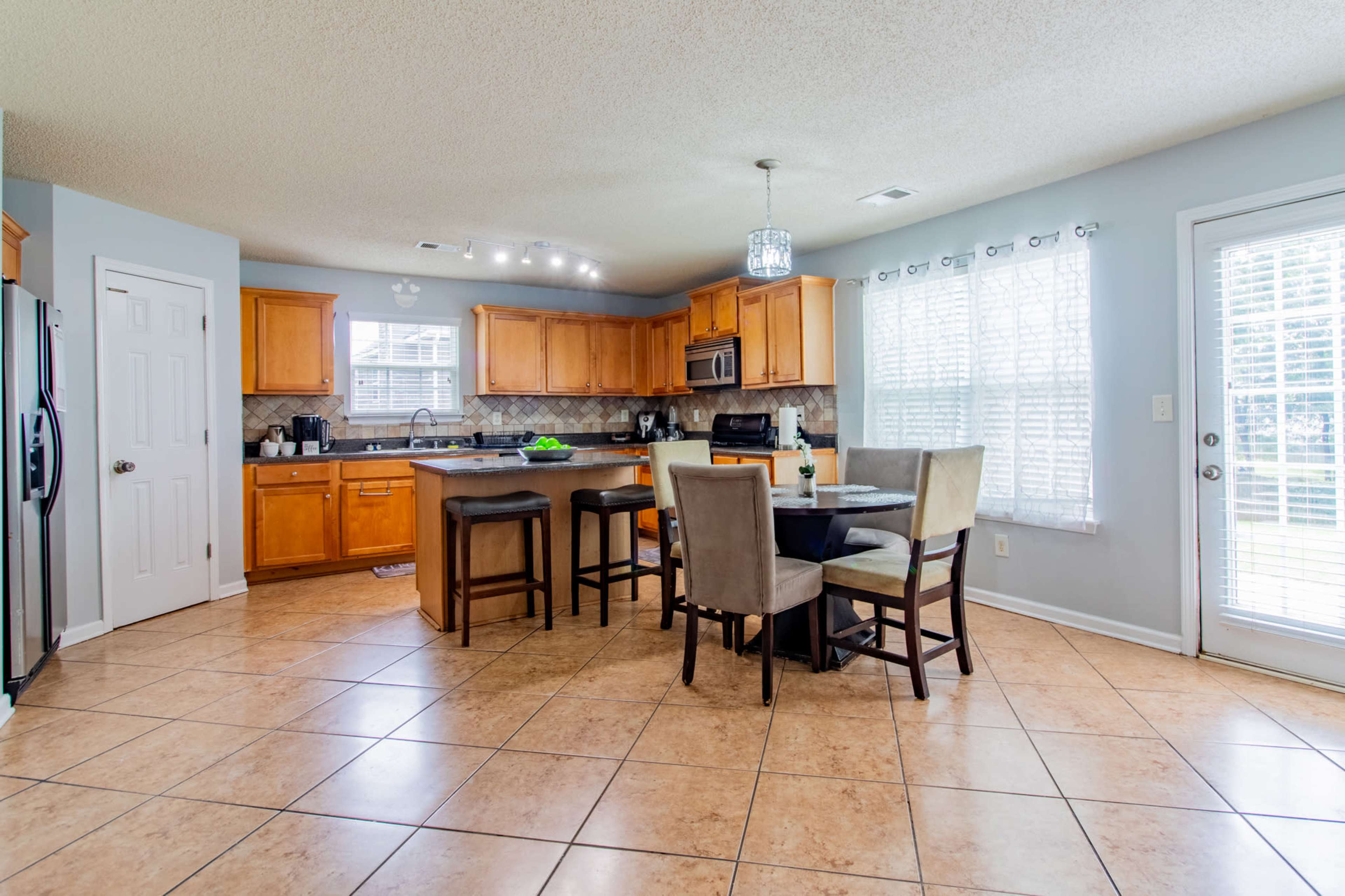 A spacious kitchen with wooden cabinets, a large island, and a dining area featuring a round table and four chairs.
