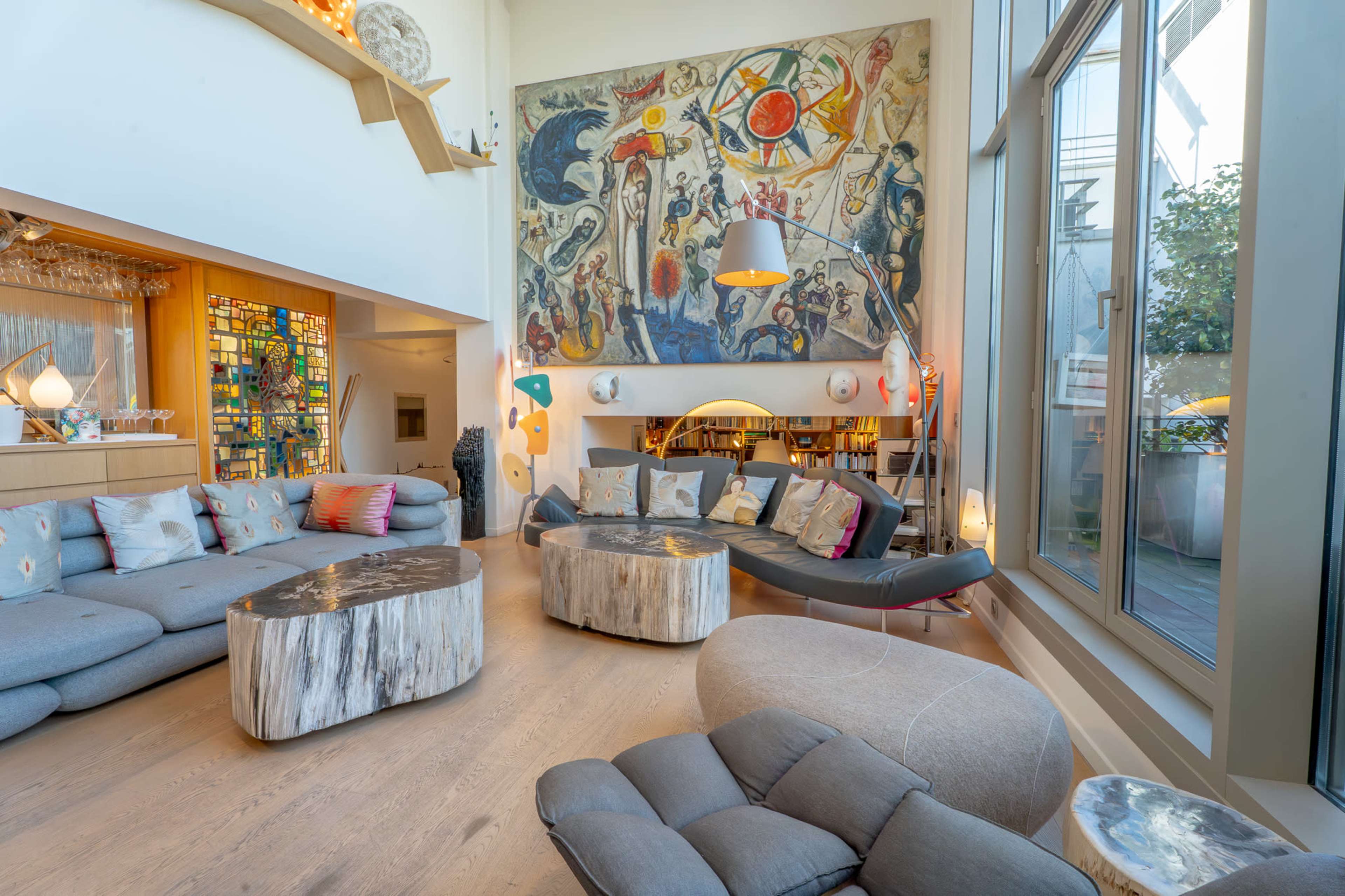 The image features a modern living room with a large mural on the wall, showcasing a variety of seating arrangements and decorative elements.