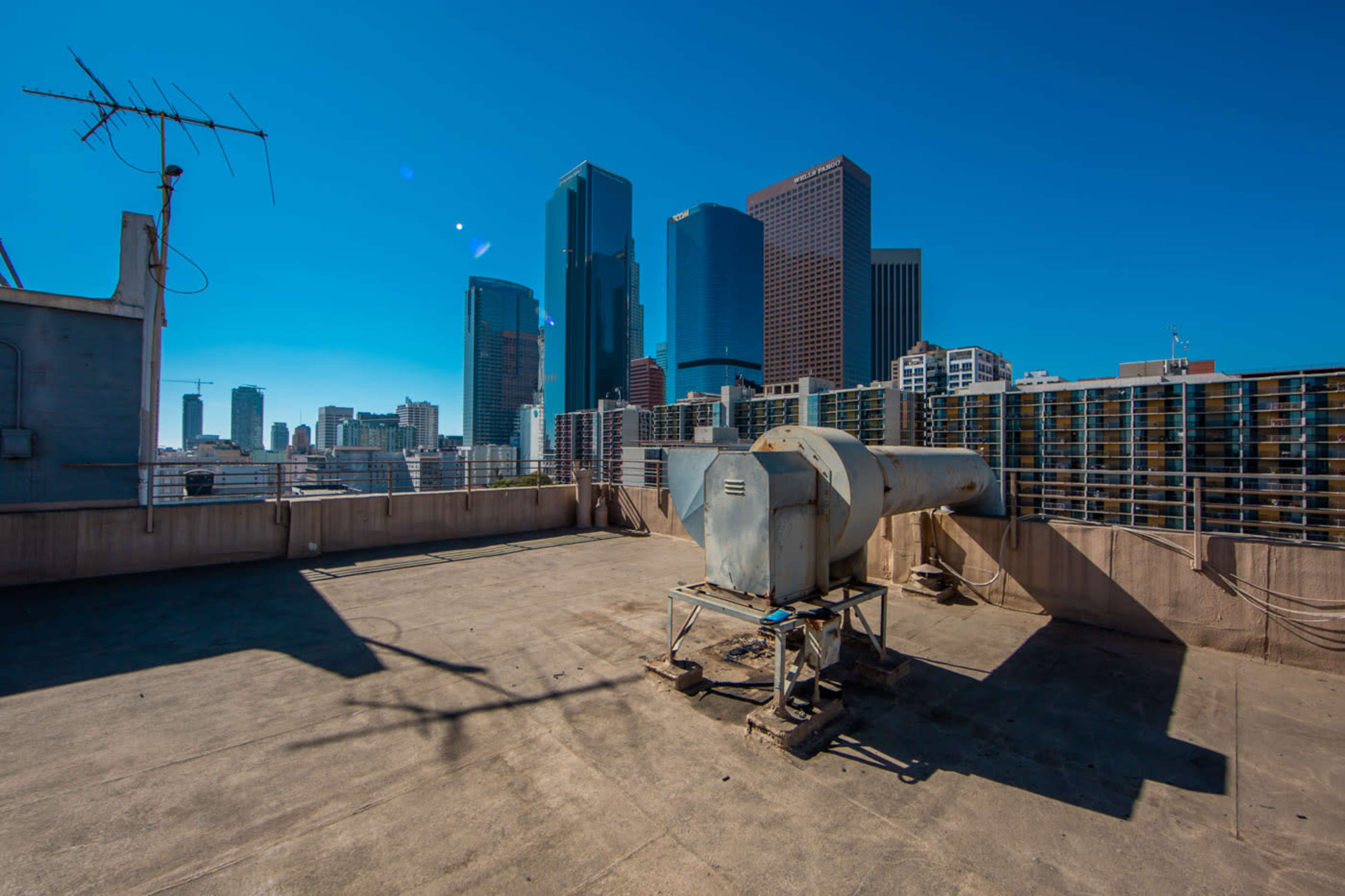 A rooftop with an air conditioning unit and a view of skyscrapers in a city skyline.