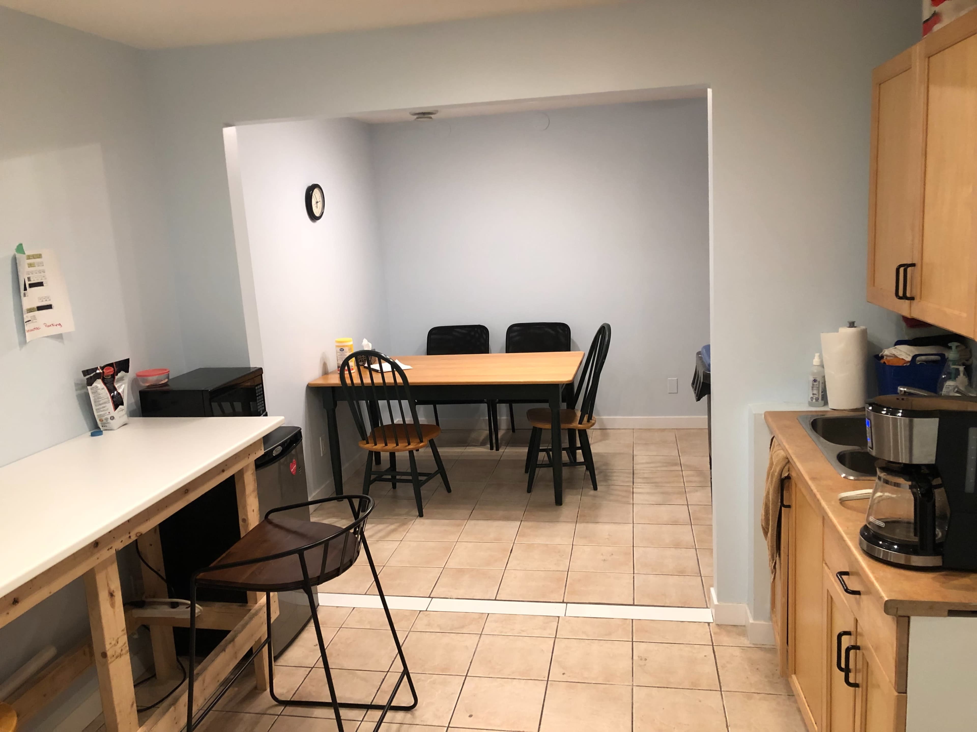 A kitchen area features a countertop and appliances on one side, with a dining table and chairs in an adjacent space.