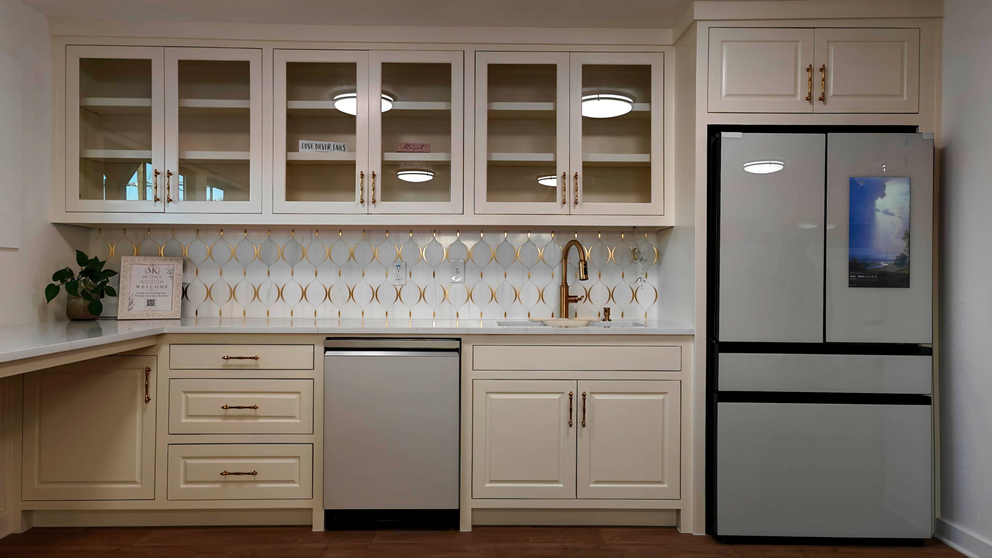 The image shows a modern kitchen featuring beige cabinetry, a stainless steel refrigerator, and a geometric tile backsplash.