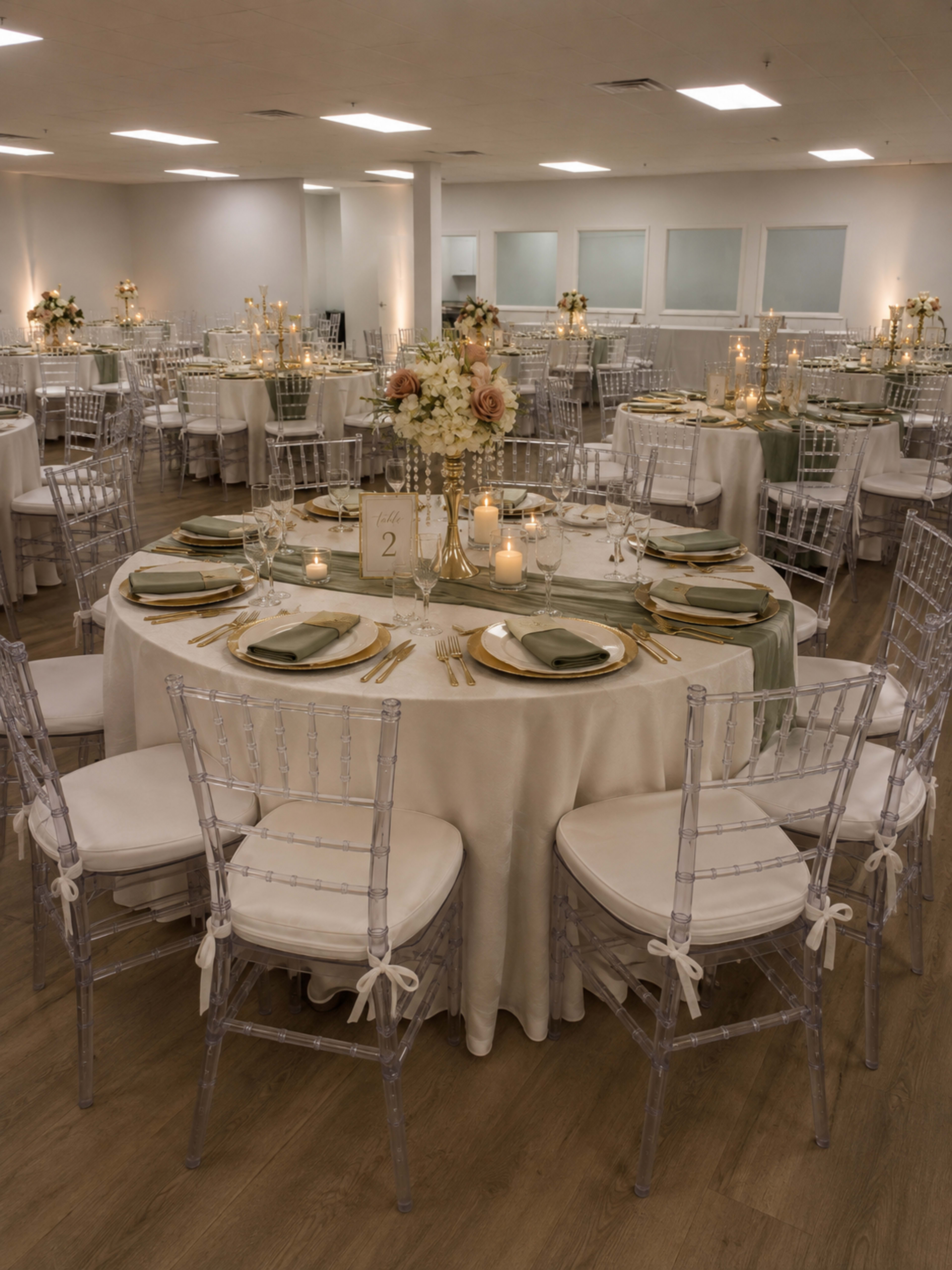 The image shows a beautifully arranged banquet hall with multiple tables set for an event, featuring elegant table settings, floral centerpieces, and soft lighting.