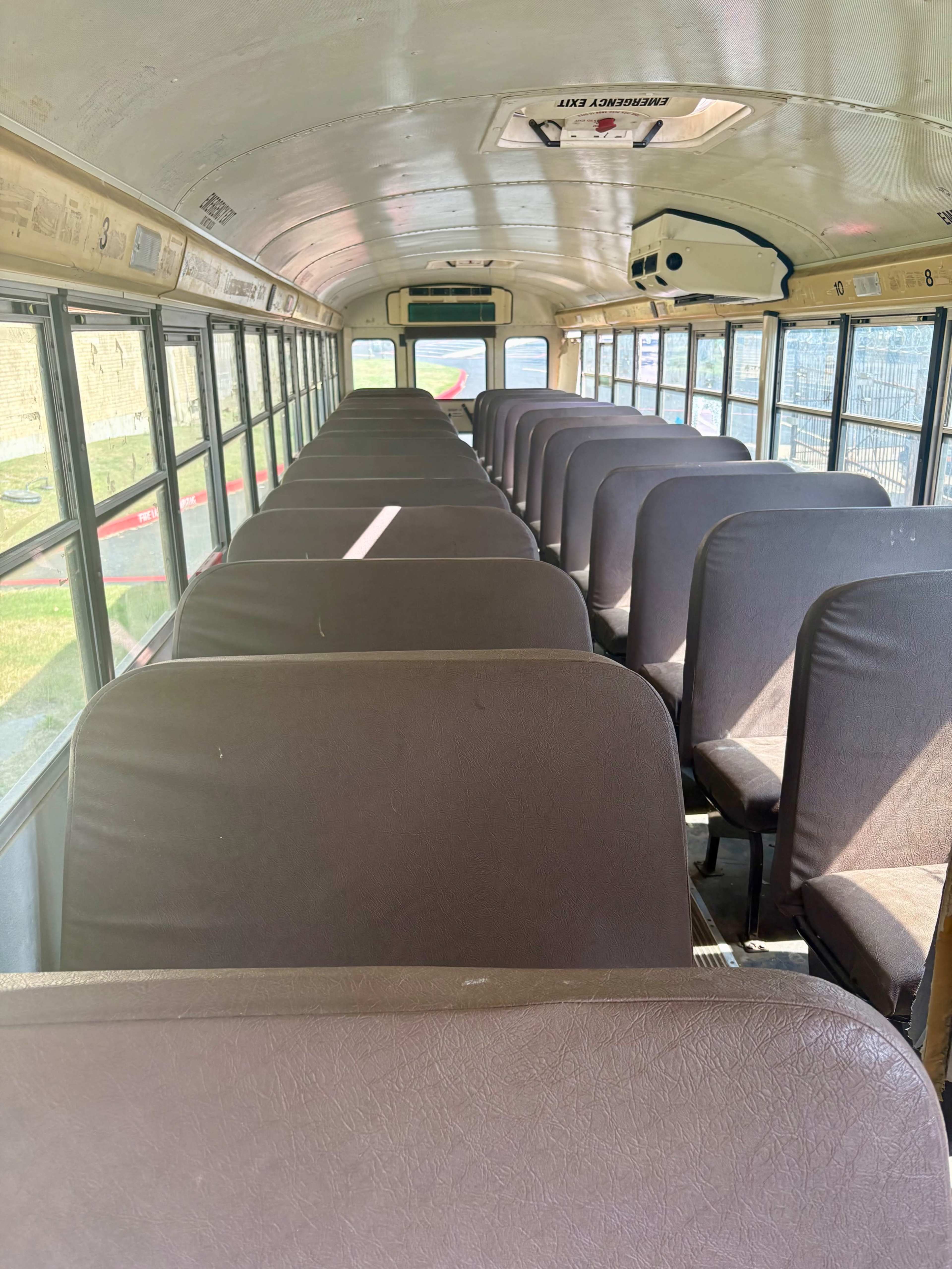 The interior of a school bus is shown, featuring rows of seats arranged in angled rows along the sides.
