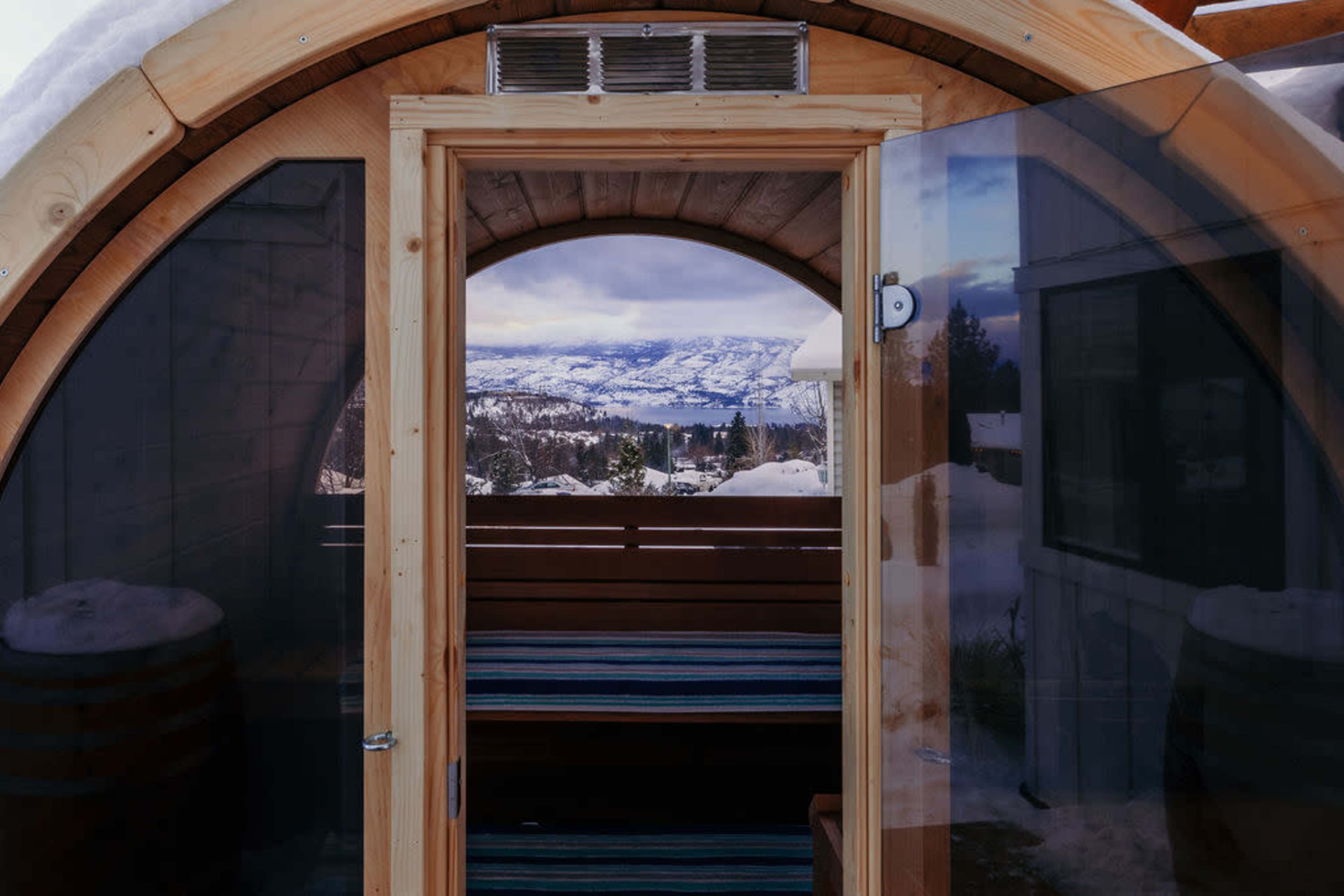 A wooden pod with a doorway opens to a snowy landscape and mountains in the distance.