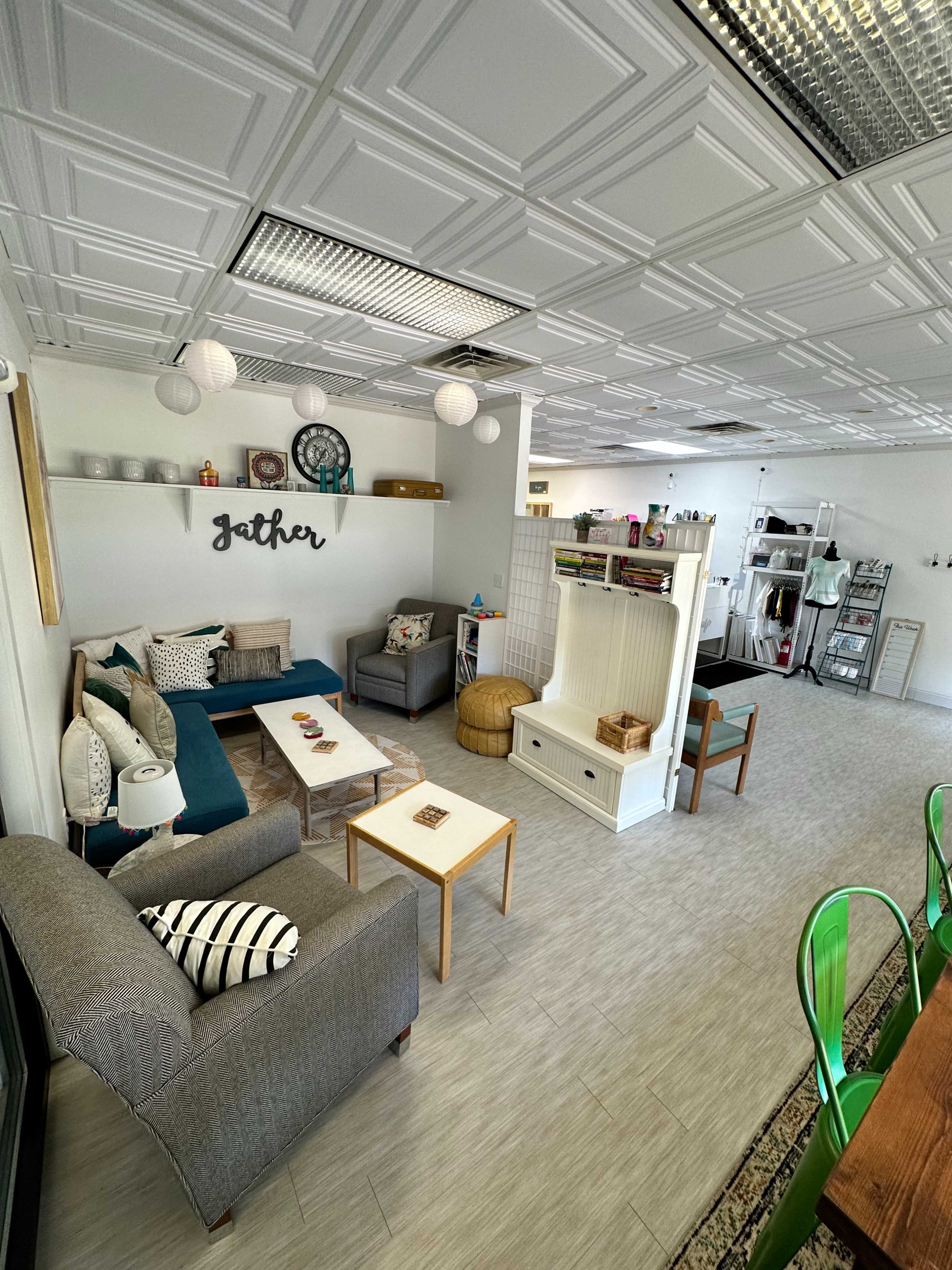 A modern communal space featuring comfortable seating, a coffee table, and decorative elements, with a dining area visible in the background.