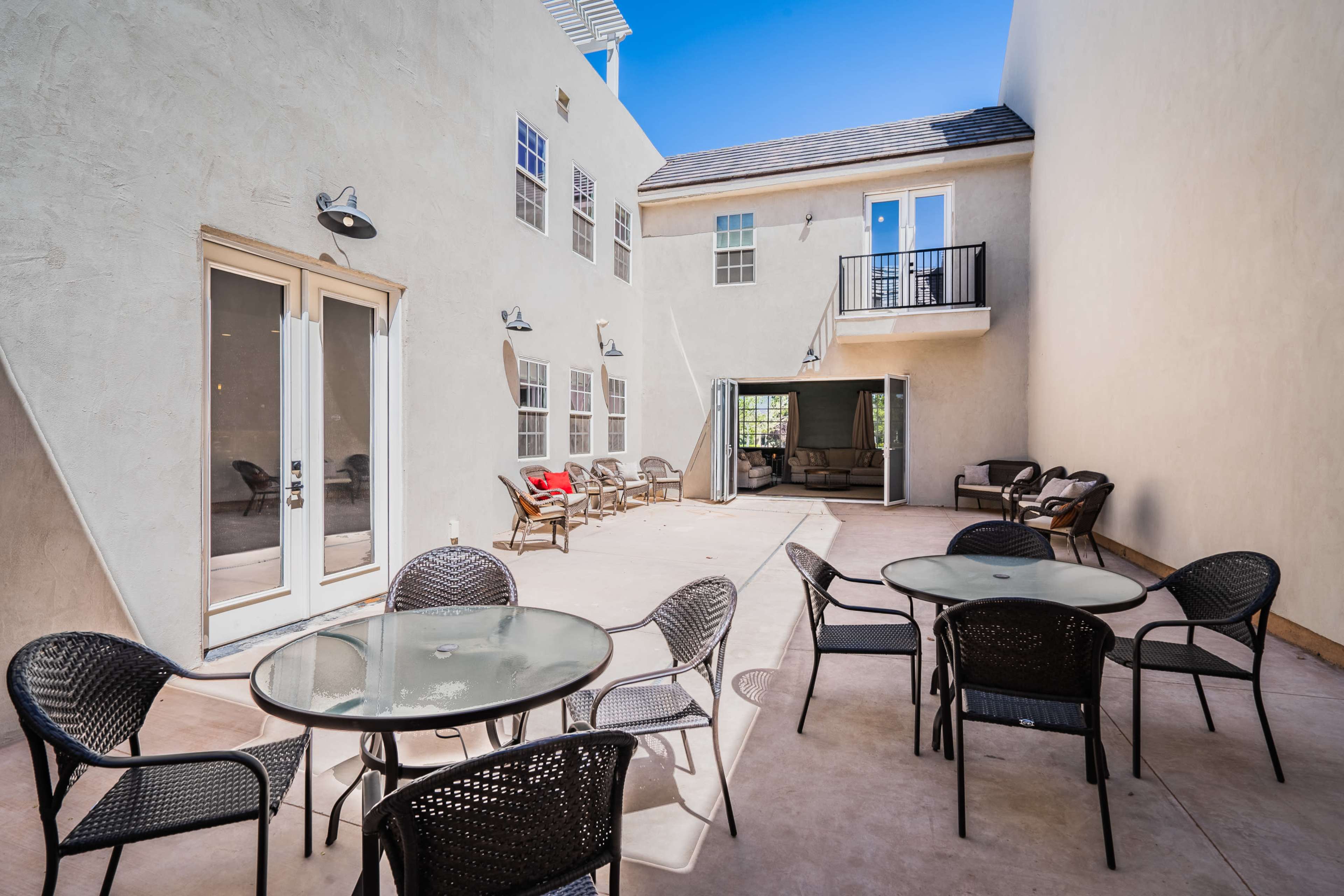 A courtyard with several tables and chairs, flanked by buildings on two sides.