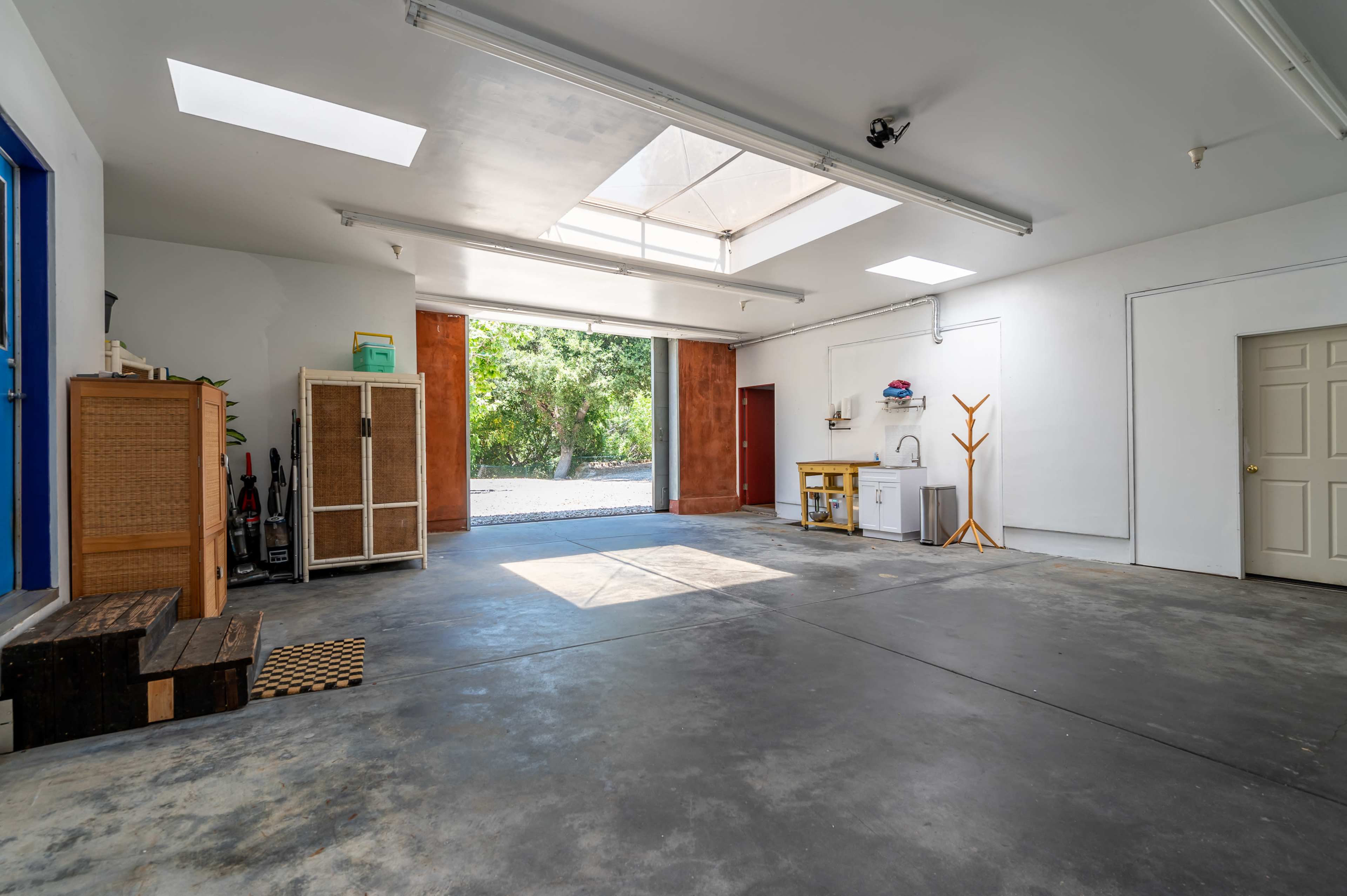 A spacious, well-lit garage with a concrete floor, large windows, and a few basic storage items along the walls.