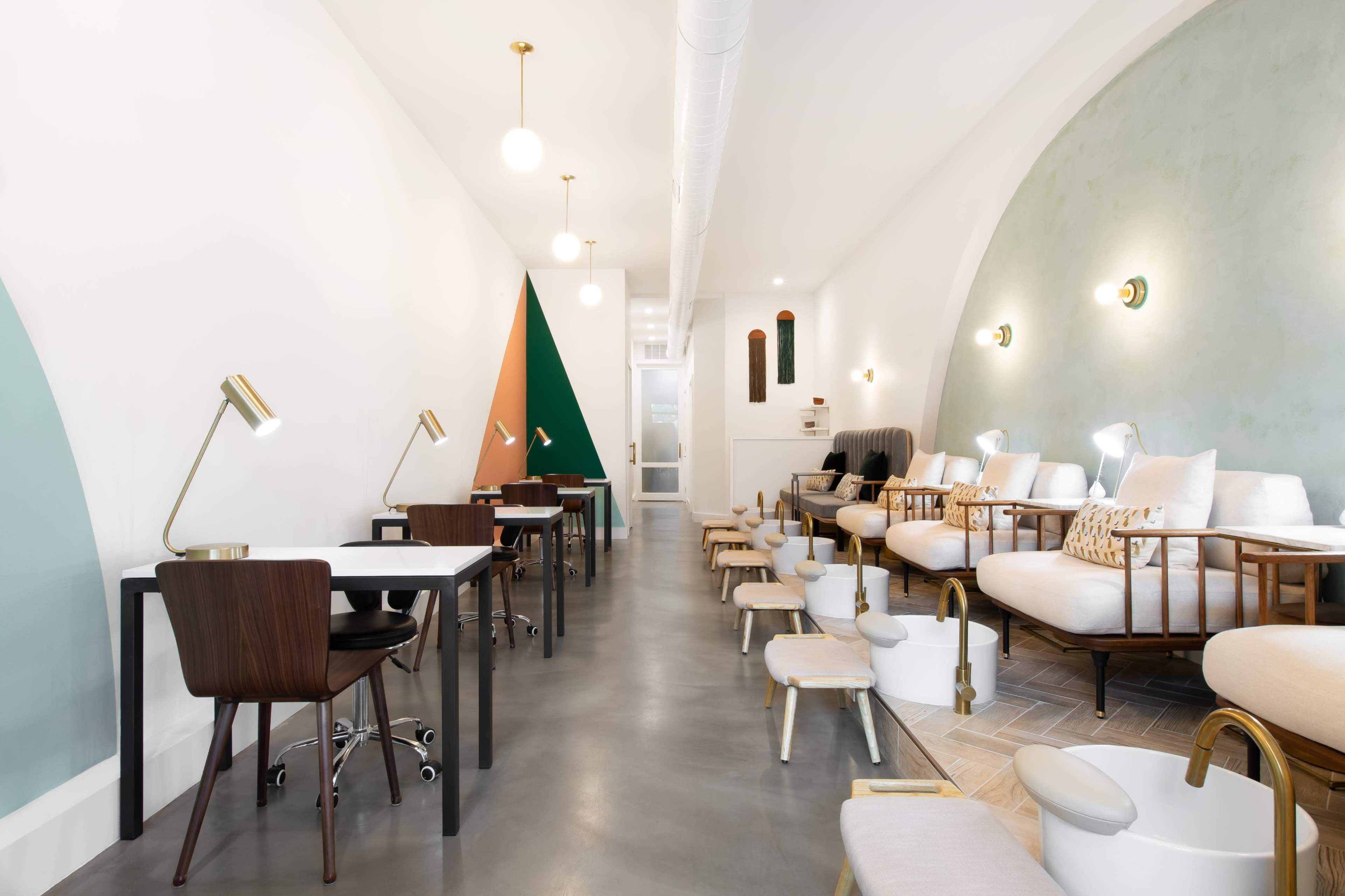 A modern salon interior featuring several workstations, comfortable seating, and a stylish color scheme with green and orange accents.