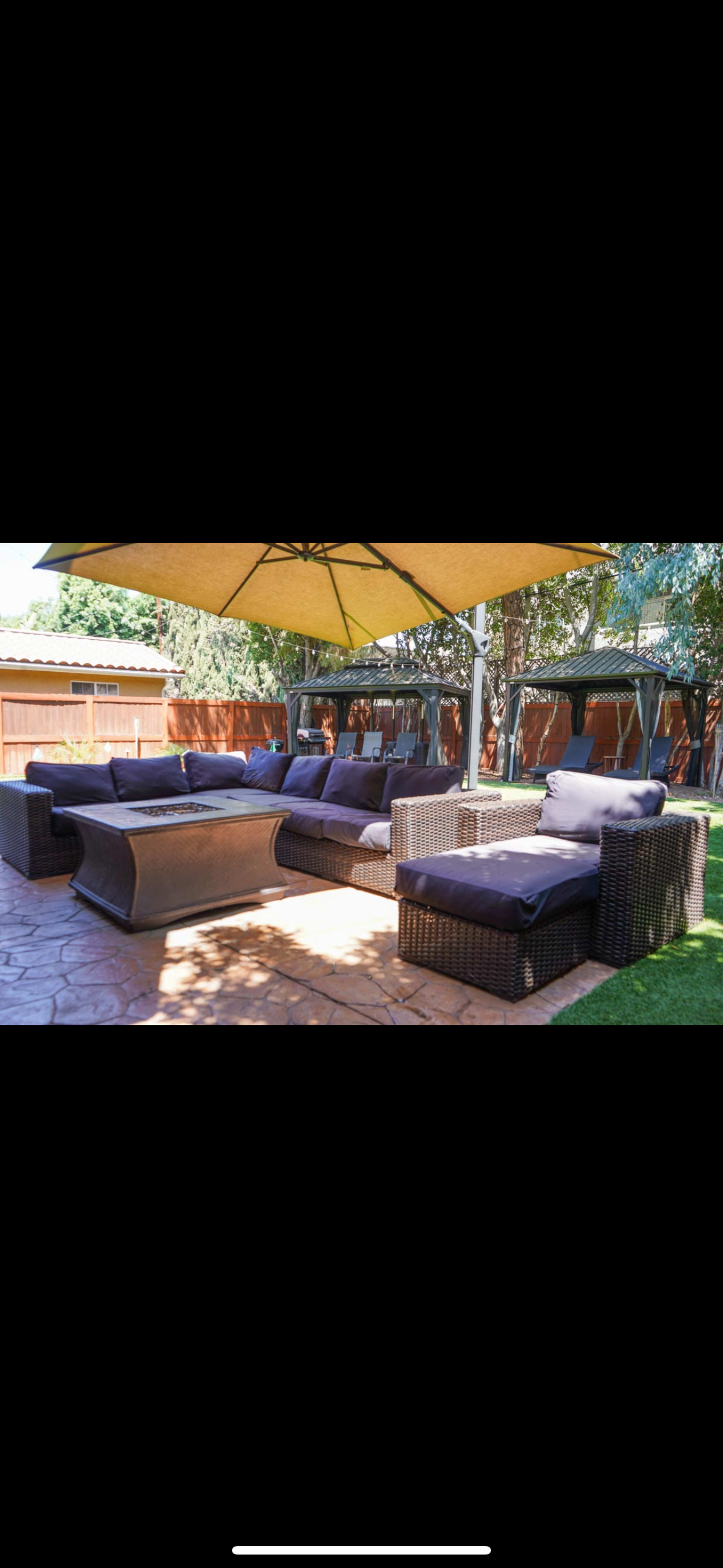 A patio area features multiple outdoor seating arrangements with cushions, a coffee table, and a large patio umbrella.