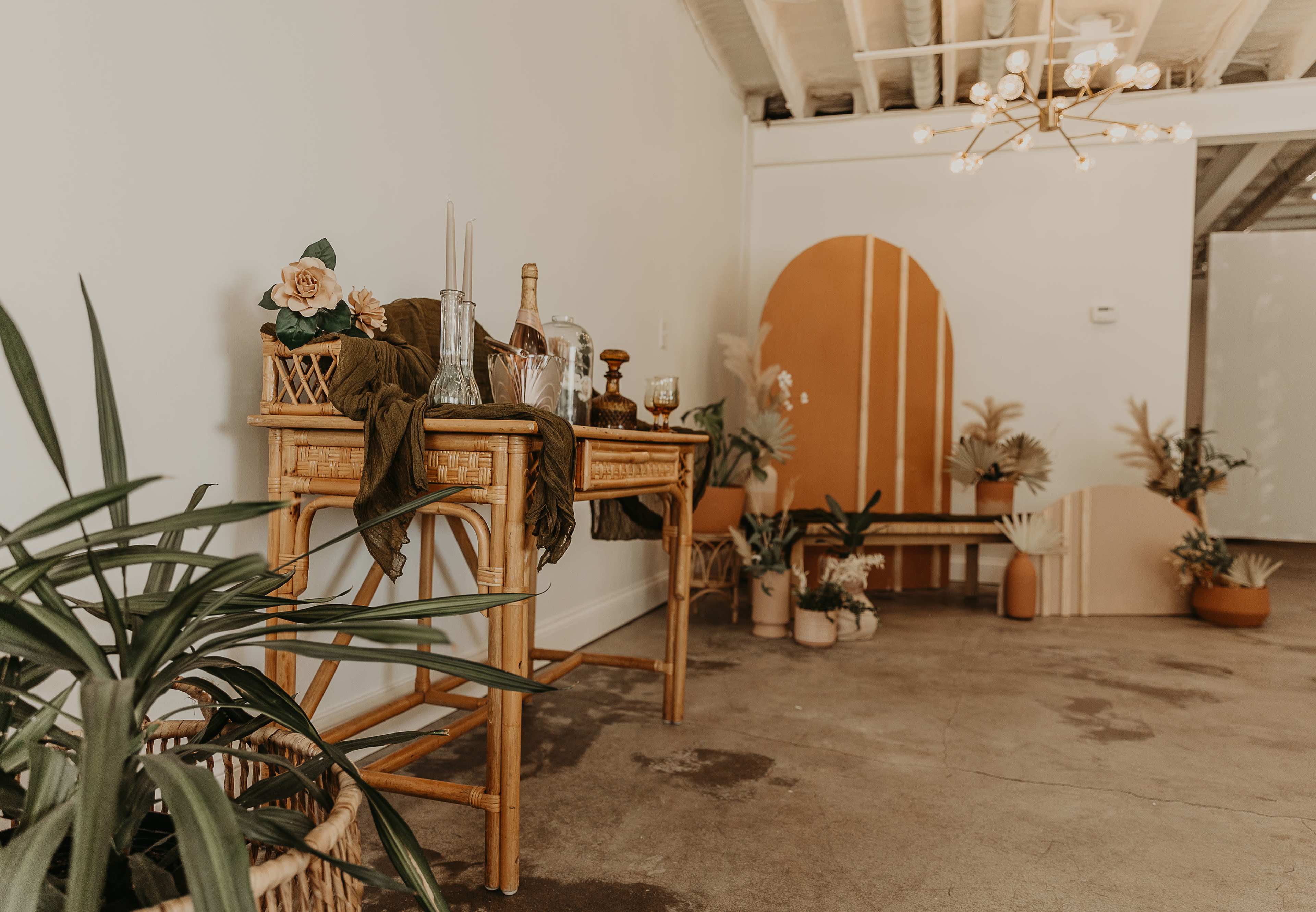 A minimalistic interior space featuring a wooden console table with various decorative items and plants against a light-colored wall.