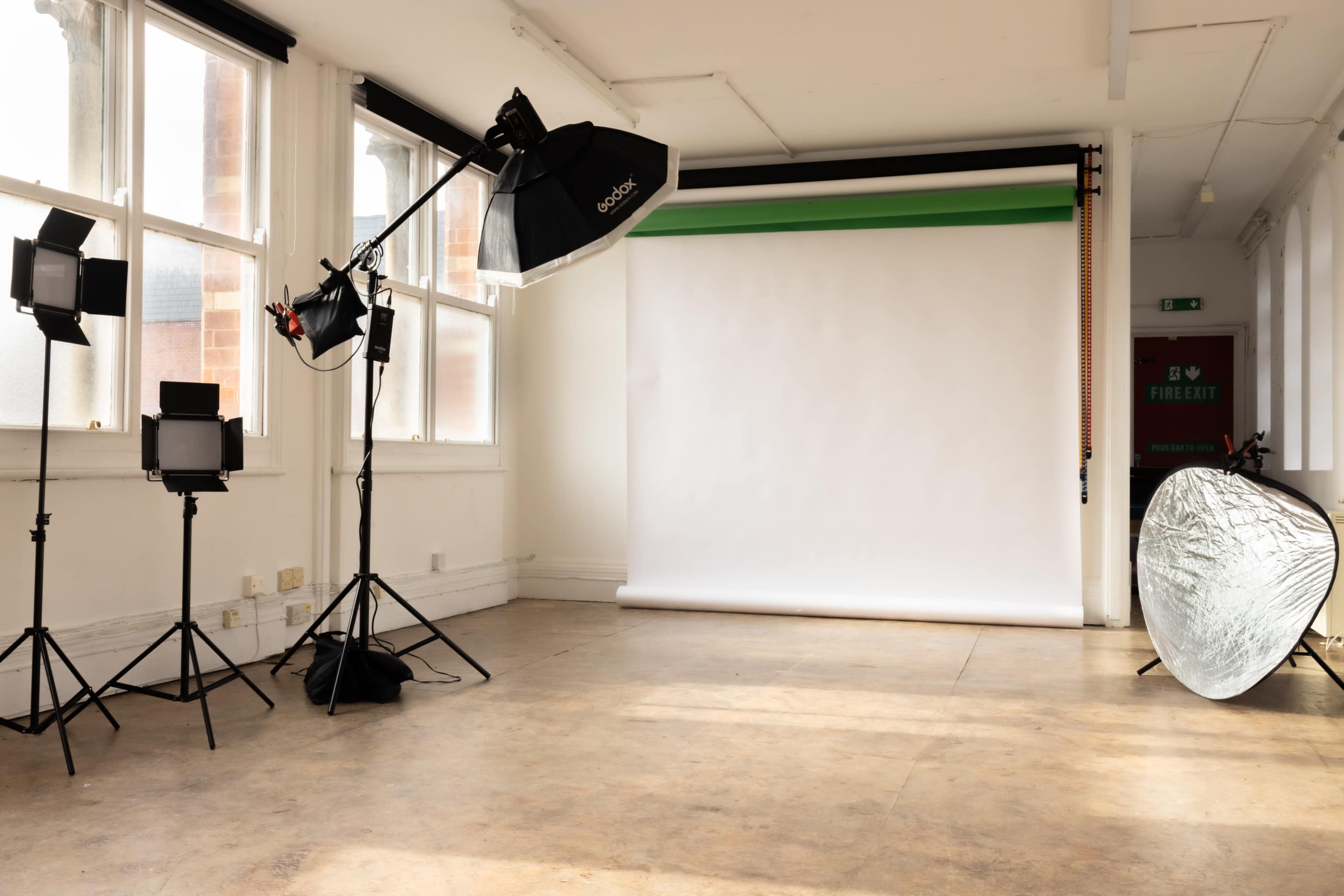 A photography studio equipped with multiple lights and a plain backdrop.