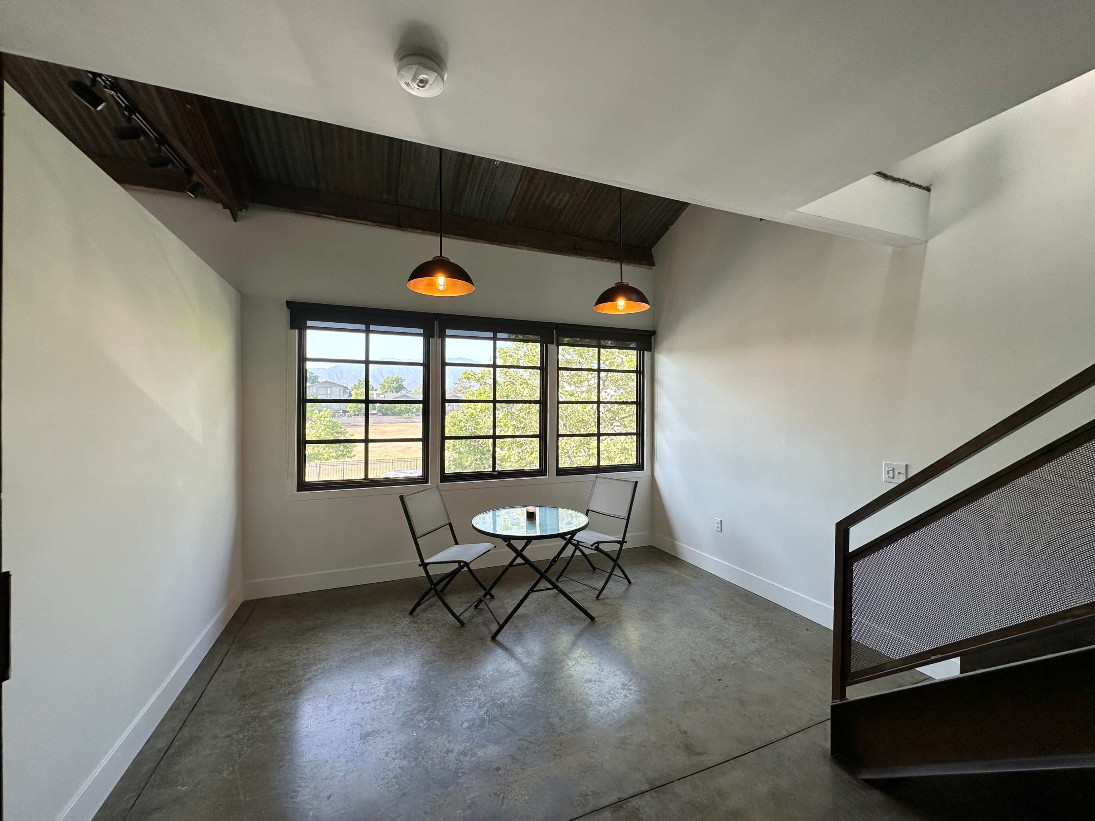 A small dining area features a round table with two chairs beside a large window overlooking a field.