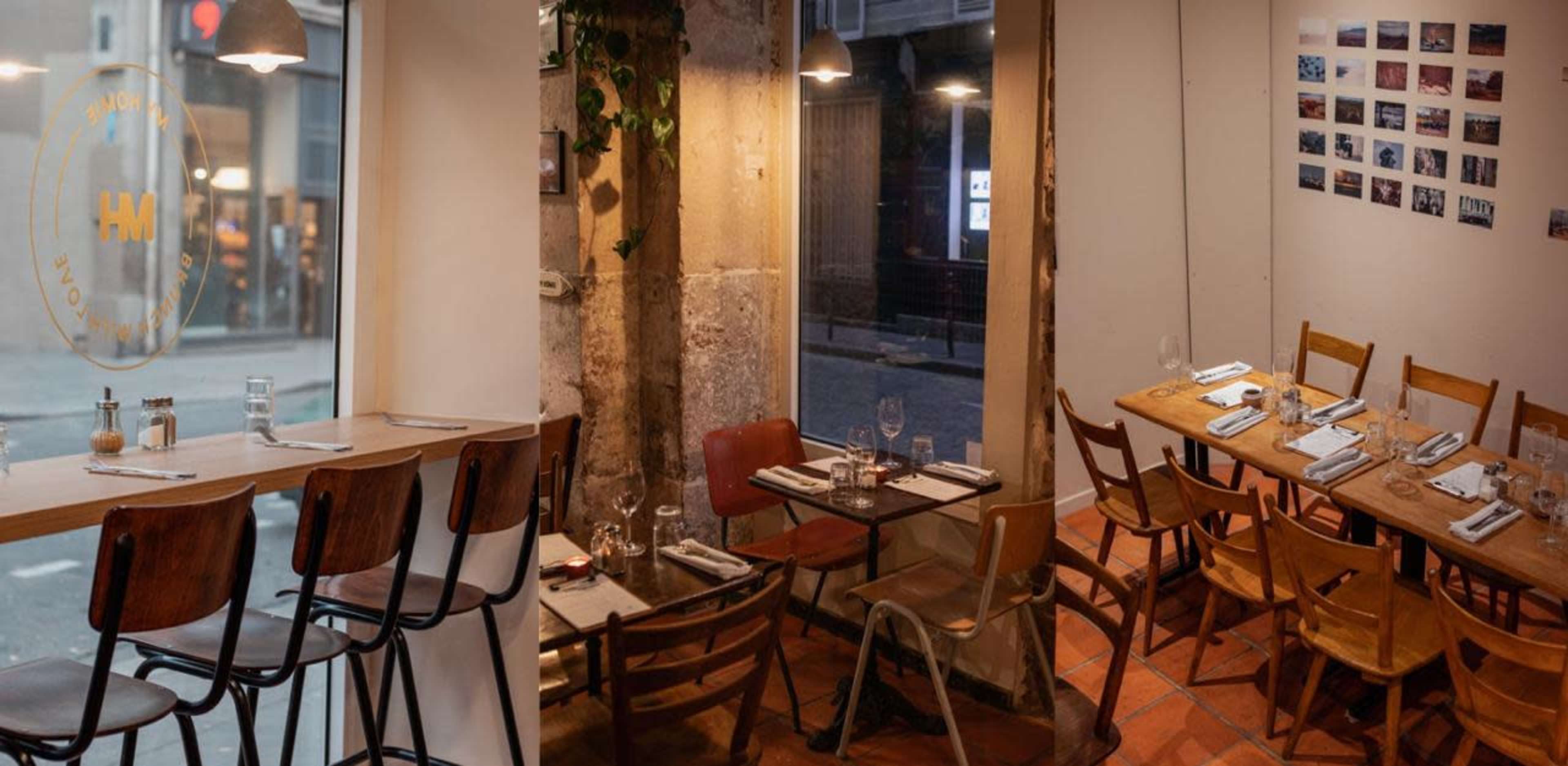 The image shows the interior of a restaurant featuring a mix of wooden tables and chairs, with windows letting in natural light and walls adorned with photographs.