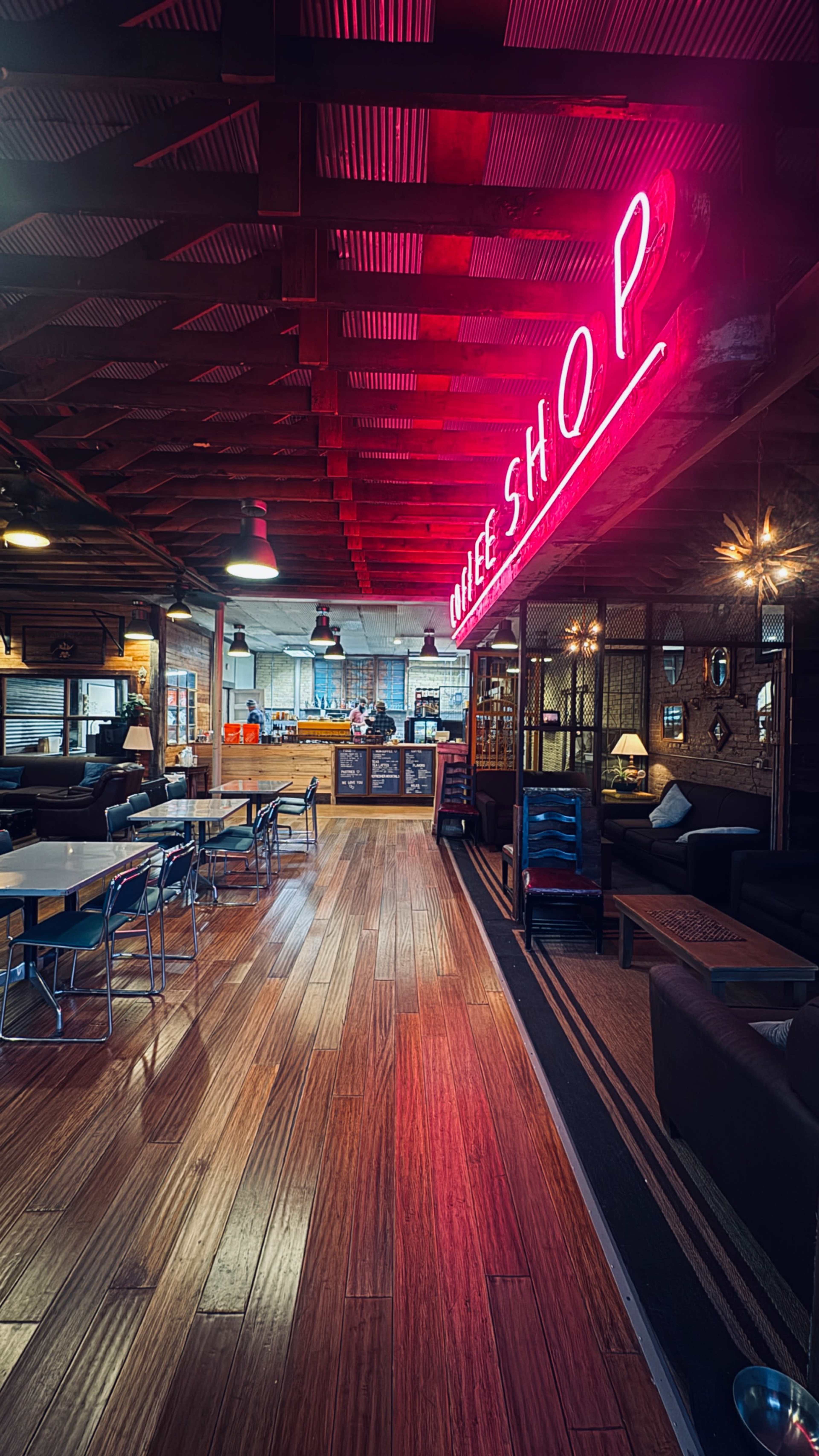The image shows the interior of a coffee shop with a neon sign that reads "COFFEE SHOP" and wooden flooring.