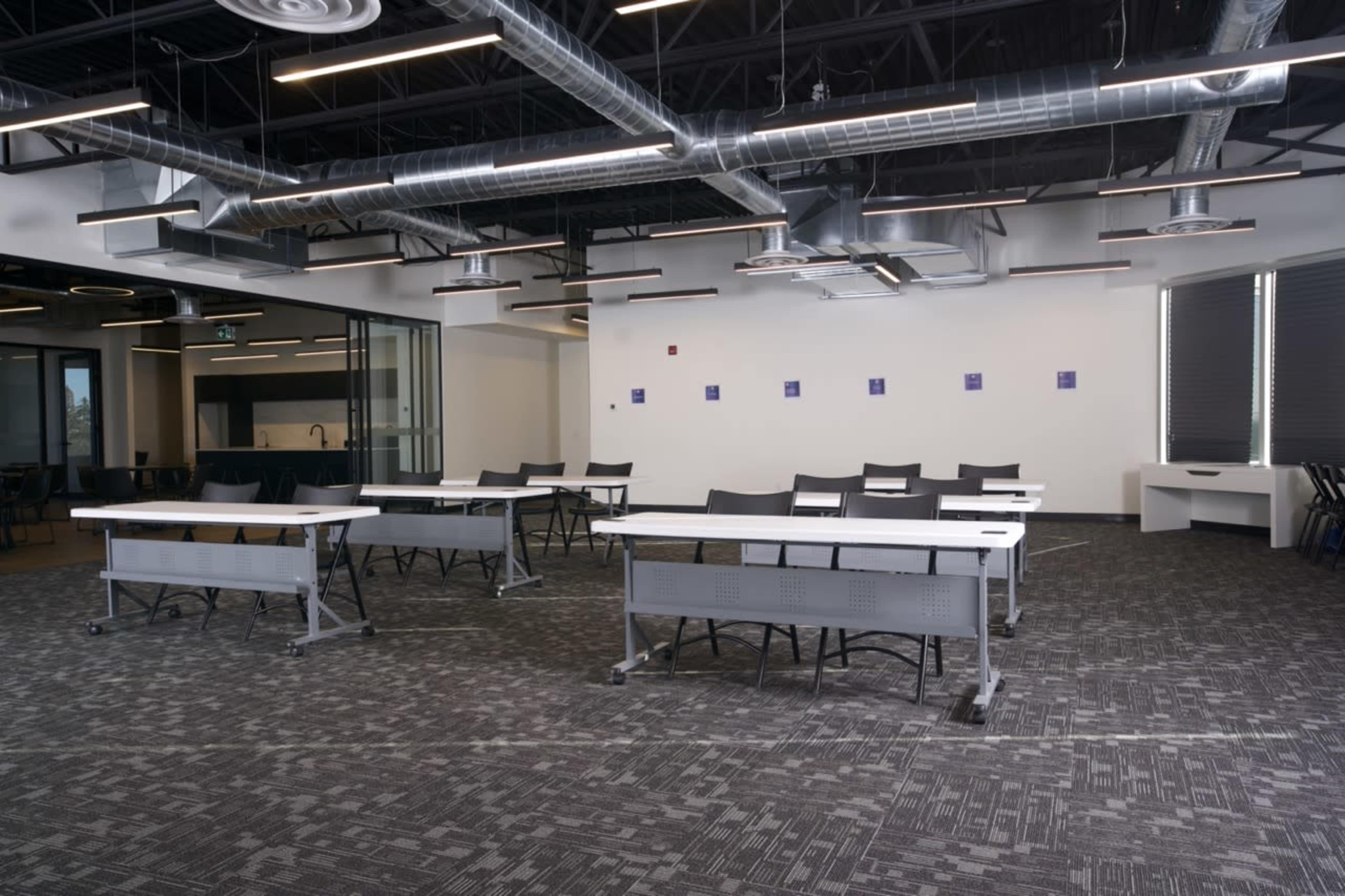A modern classroom setup with multiple tables arranged in a spacious, well-lit area.
