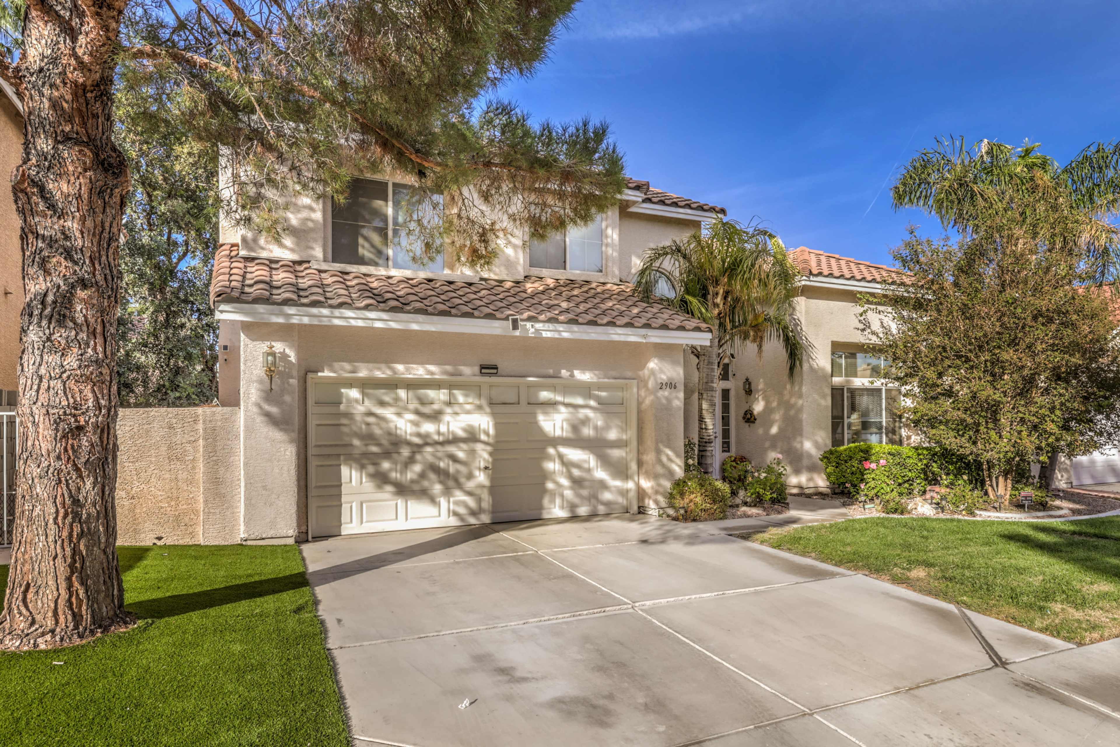 A two-story house with a tiled roof, a two-car garage, and a well-maintained front yard.
