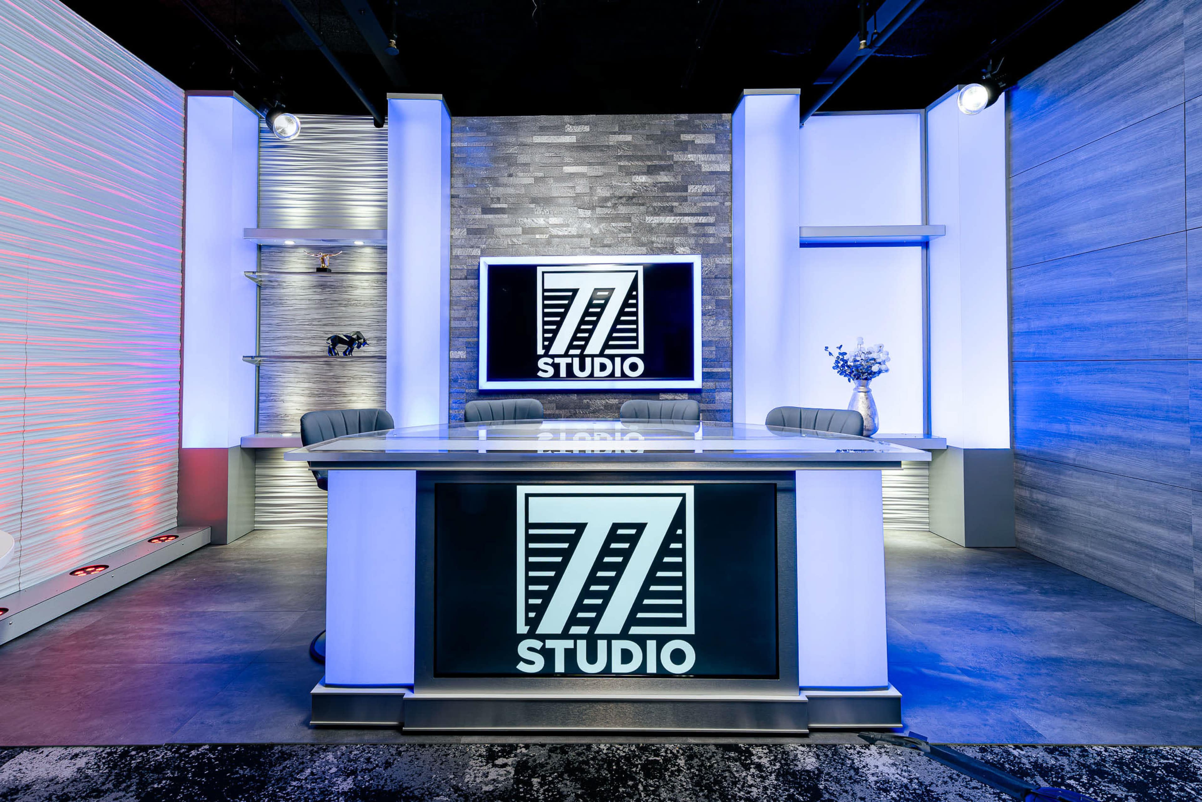 The image shows a modern studio setup with a large desk, a screen displaying "Z STUDIO," and ambient lighting on the walls.