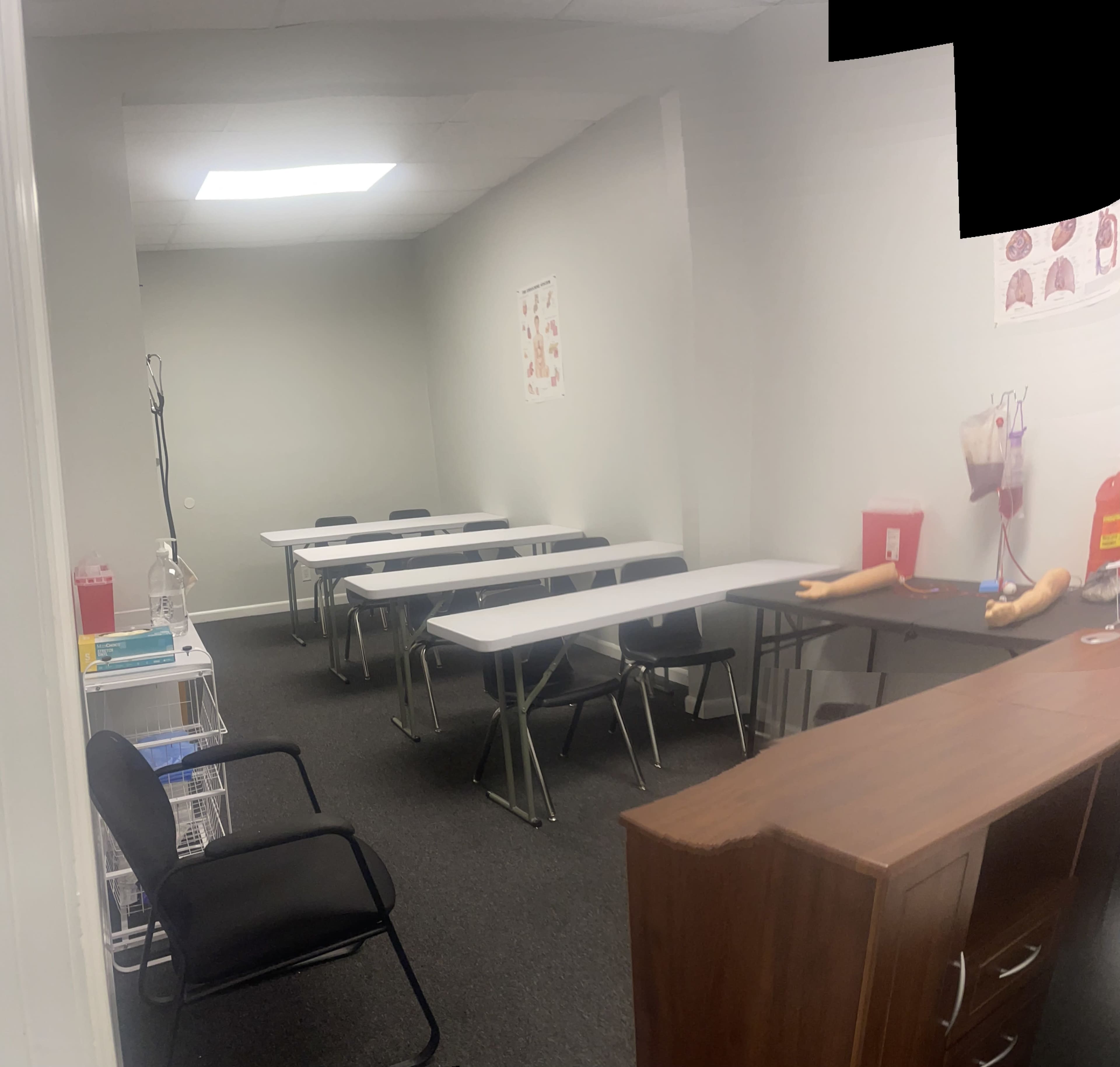 A classroom with several rows of folding tables and chairs arranged in a well-lit, empty space.
