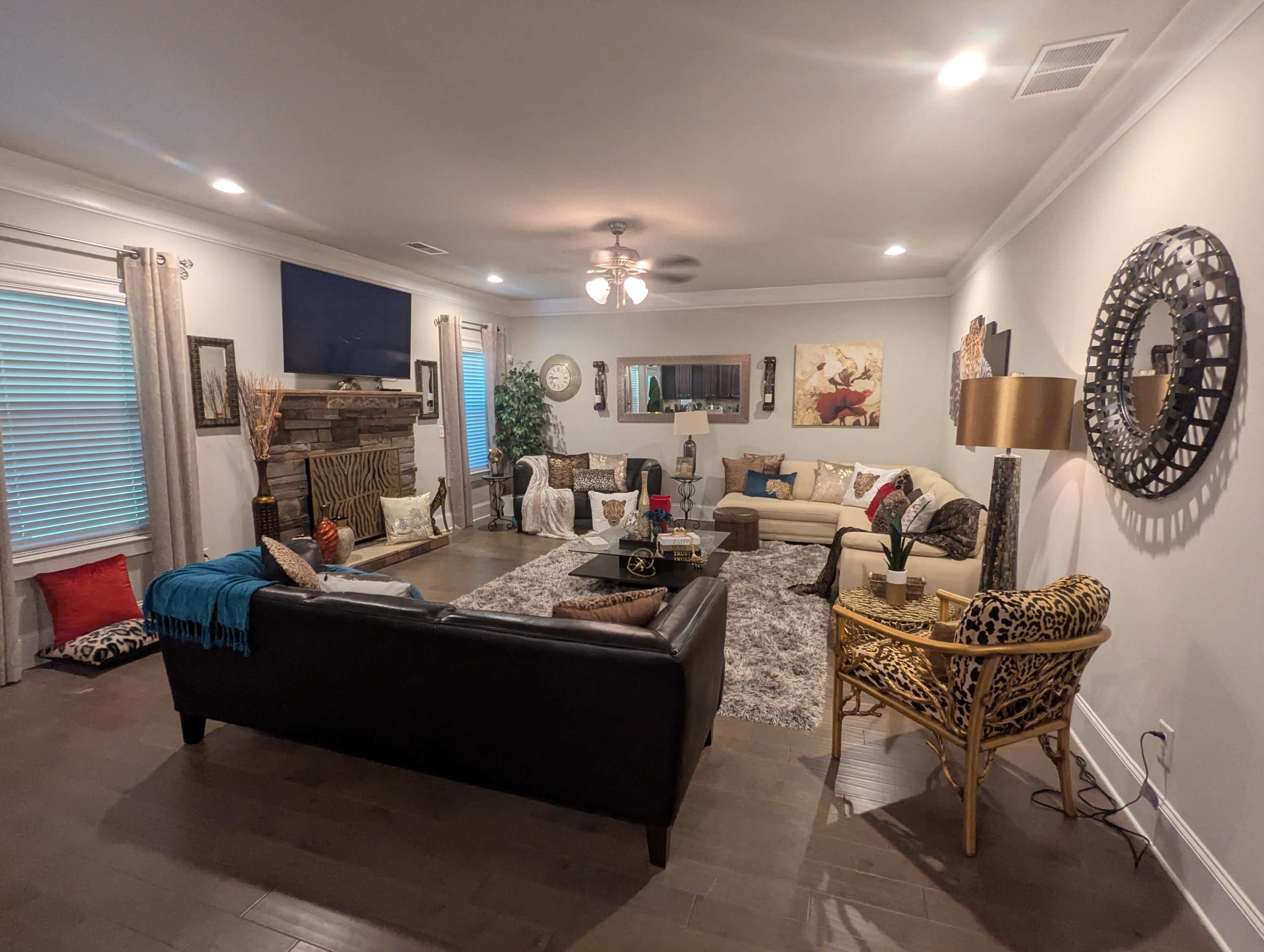 The spacious living room features a mix of seating options, a fireplace, a large rug, and decorative elements such as art, plants, and pillows.