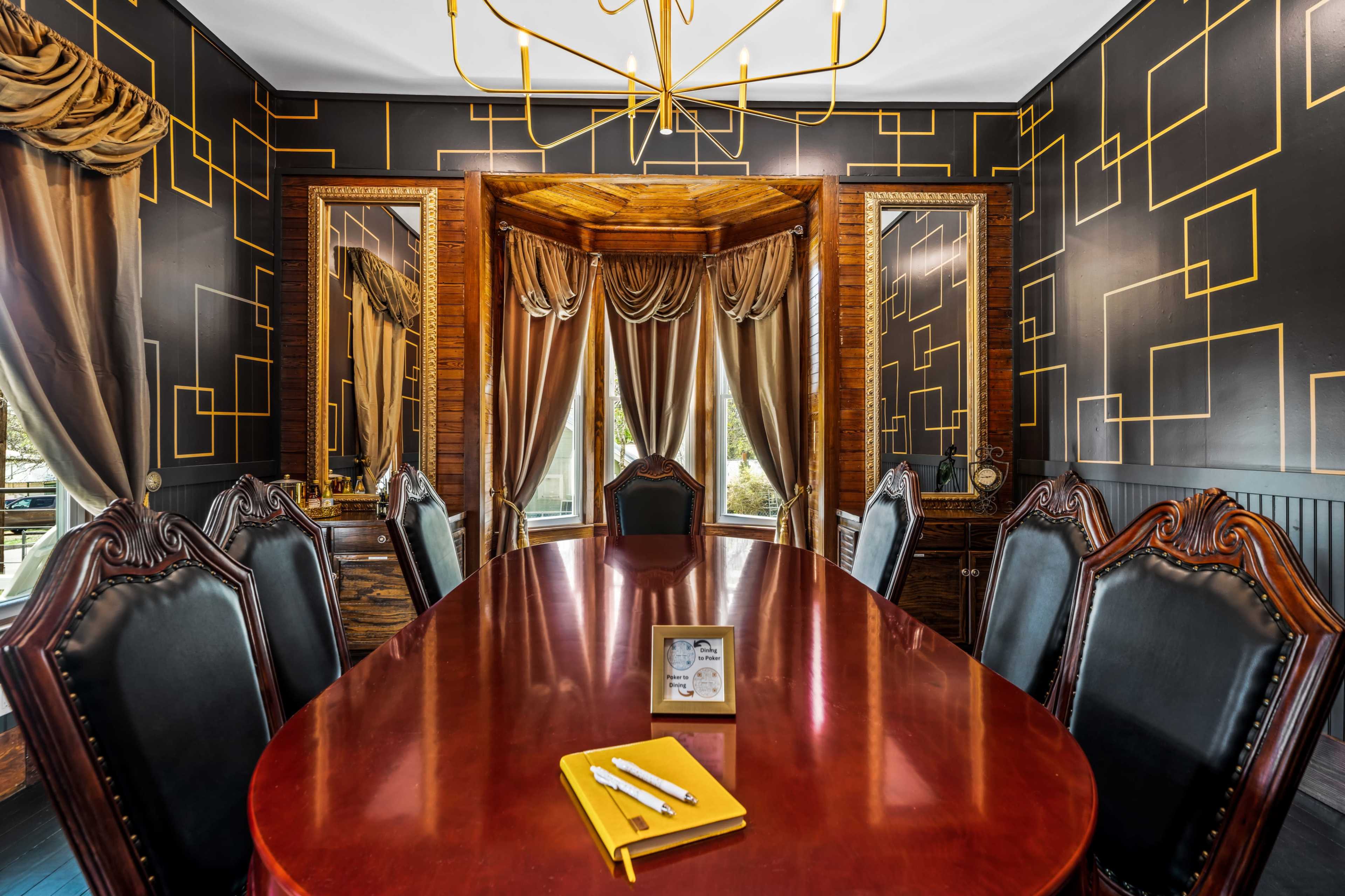 A large, elegant conference room features a polished wooden table surrounded by ornate chairs, with dark patterned wallpaper and mirrored walls.