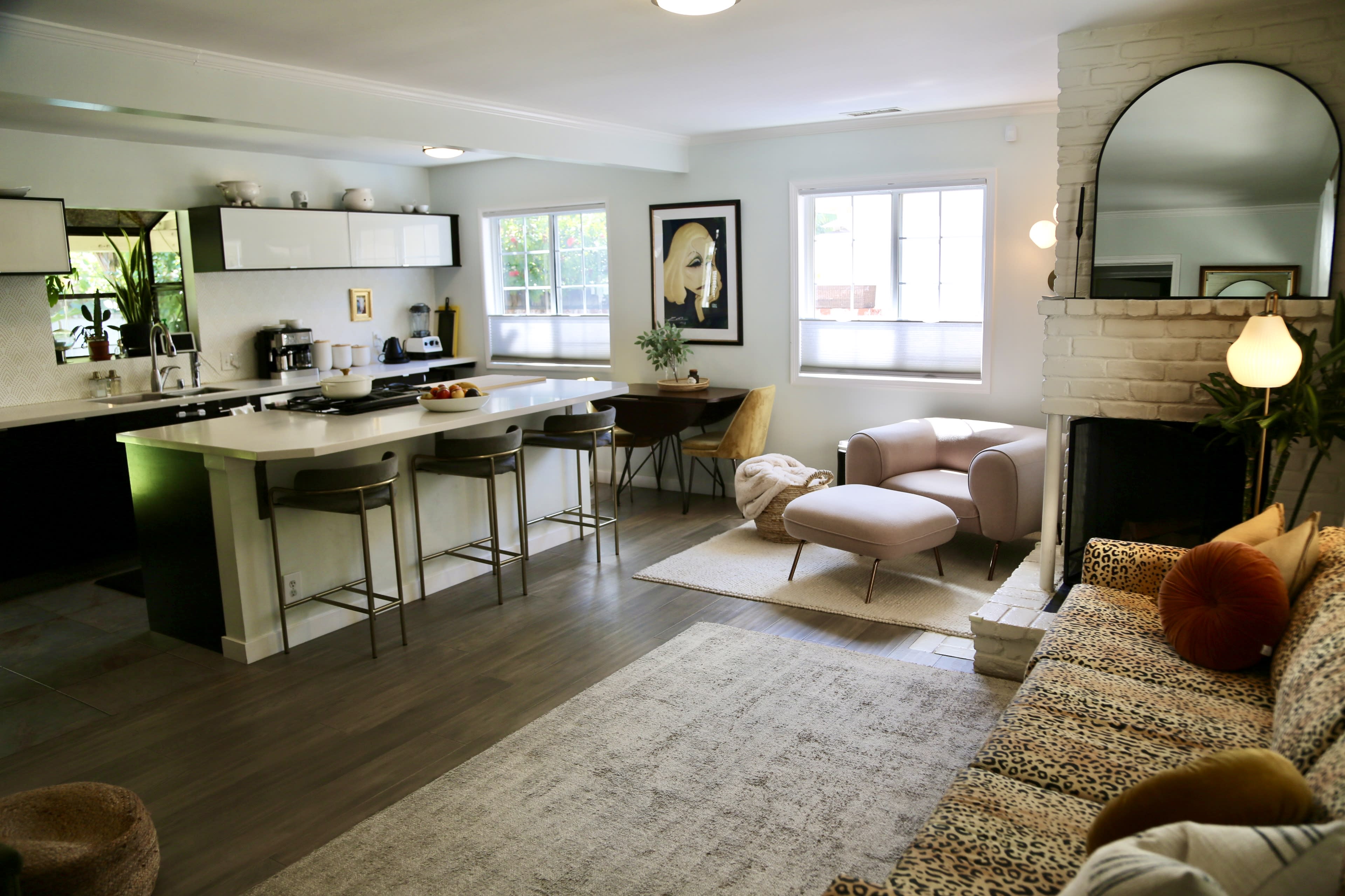 A modern living room and kitchen area with a plush sofa, dining table, and a sleek kitchen island.