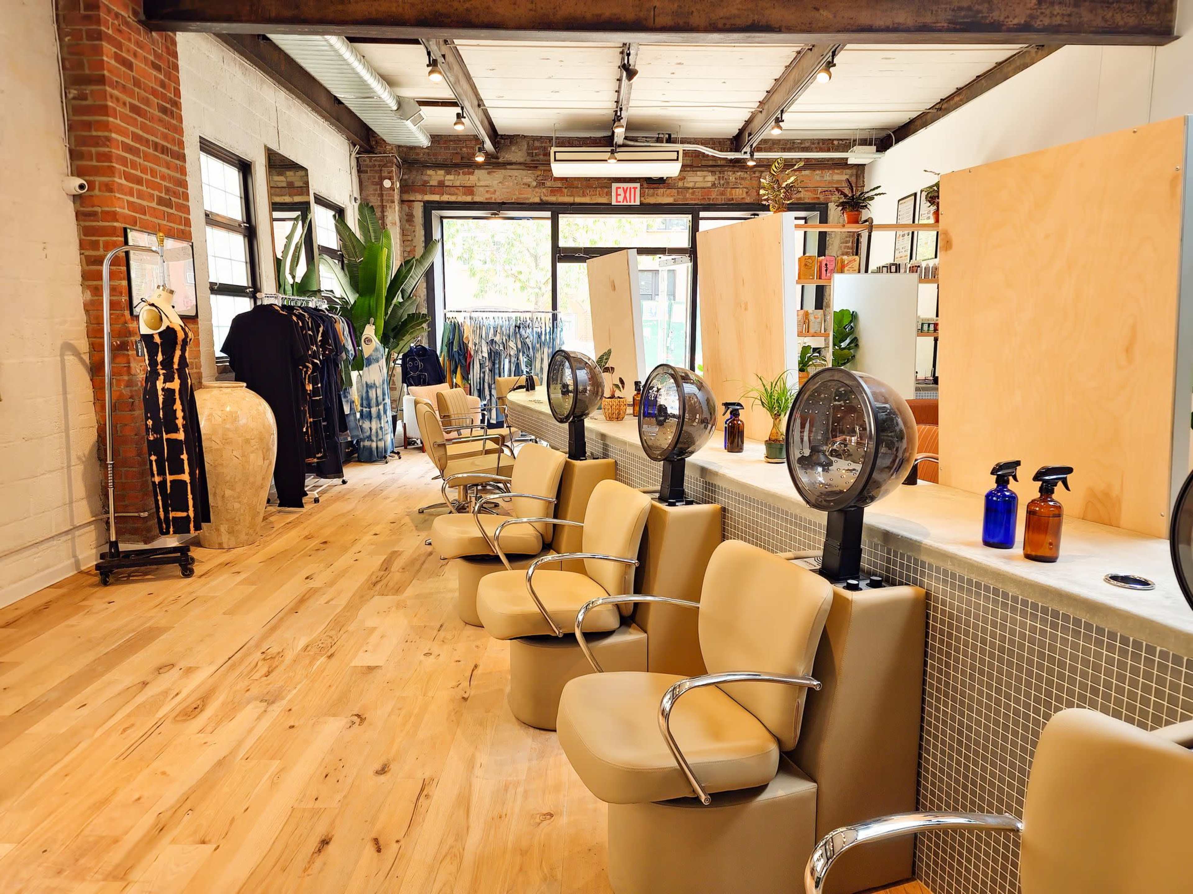 A hair salon with several styling chairs, hairdryers, and a clothing display along the side.