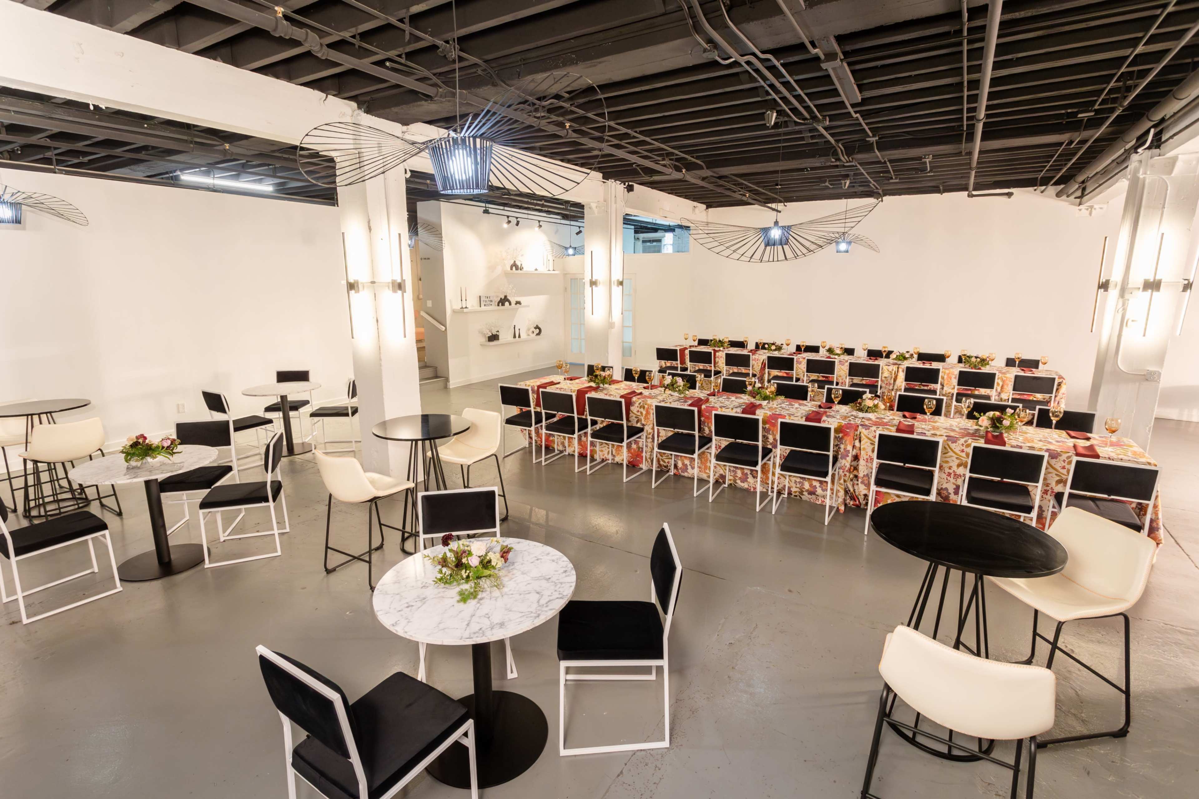 A spacious event venue arranged with tables and chairs, featuring a central dining area adorned with floral table settings.