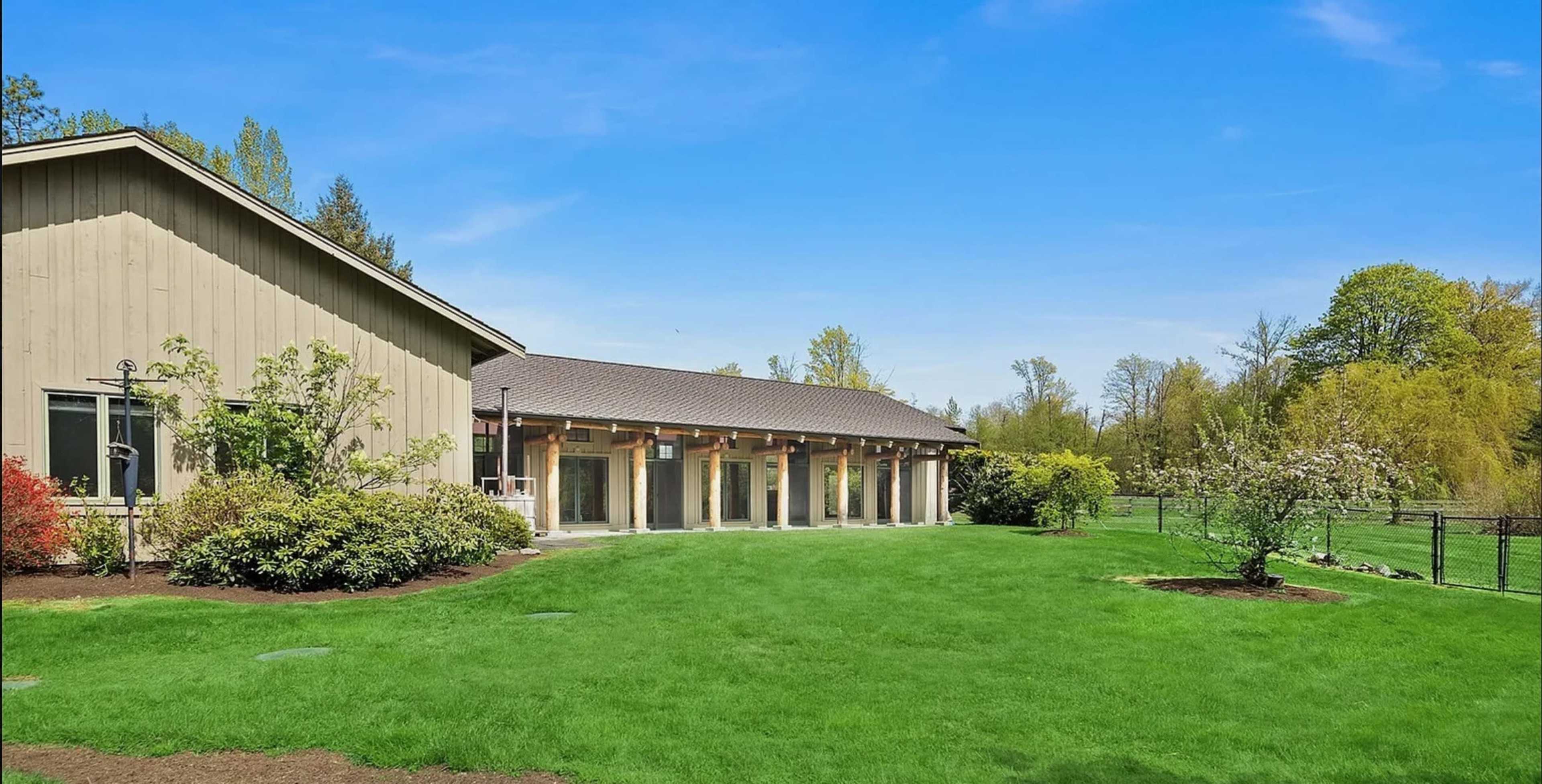 A single-story building with multiple columns, surrounded by a green lawn and trees under a clear blue sky.