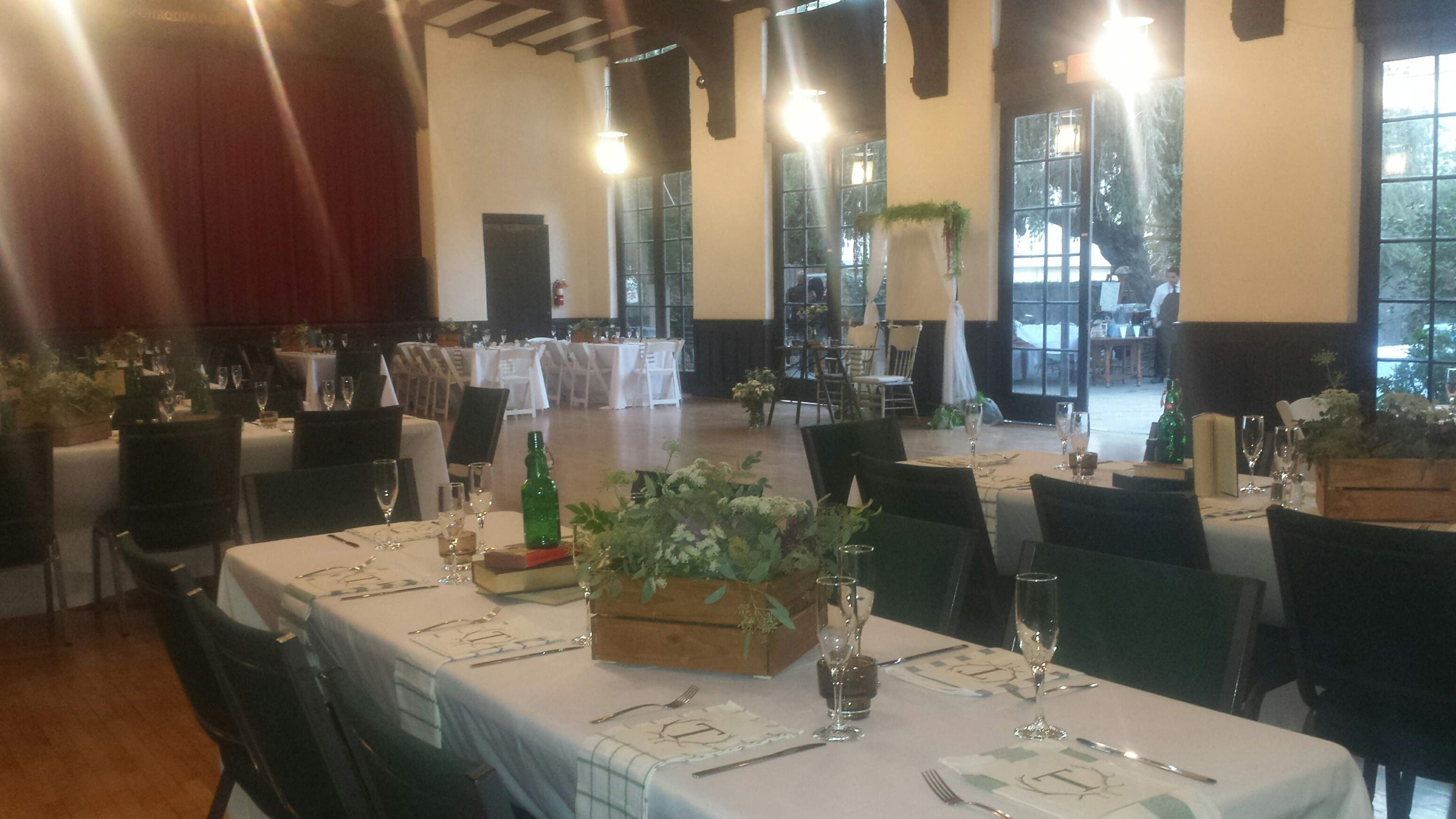 A dining hall arranged for an event, with long tables set for a meal and a stage in the background.