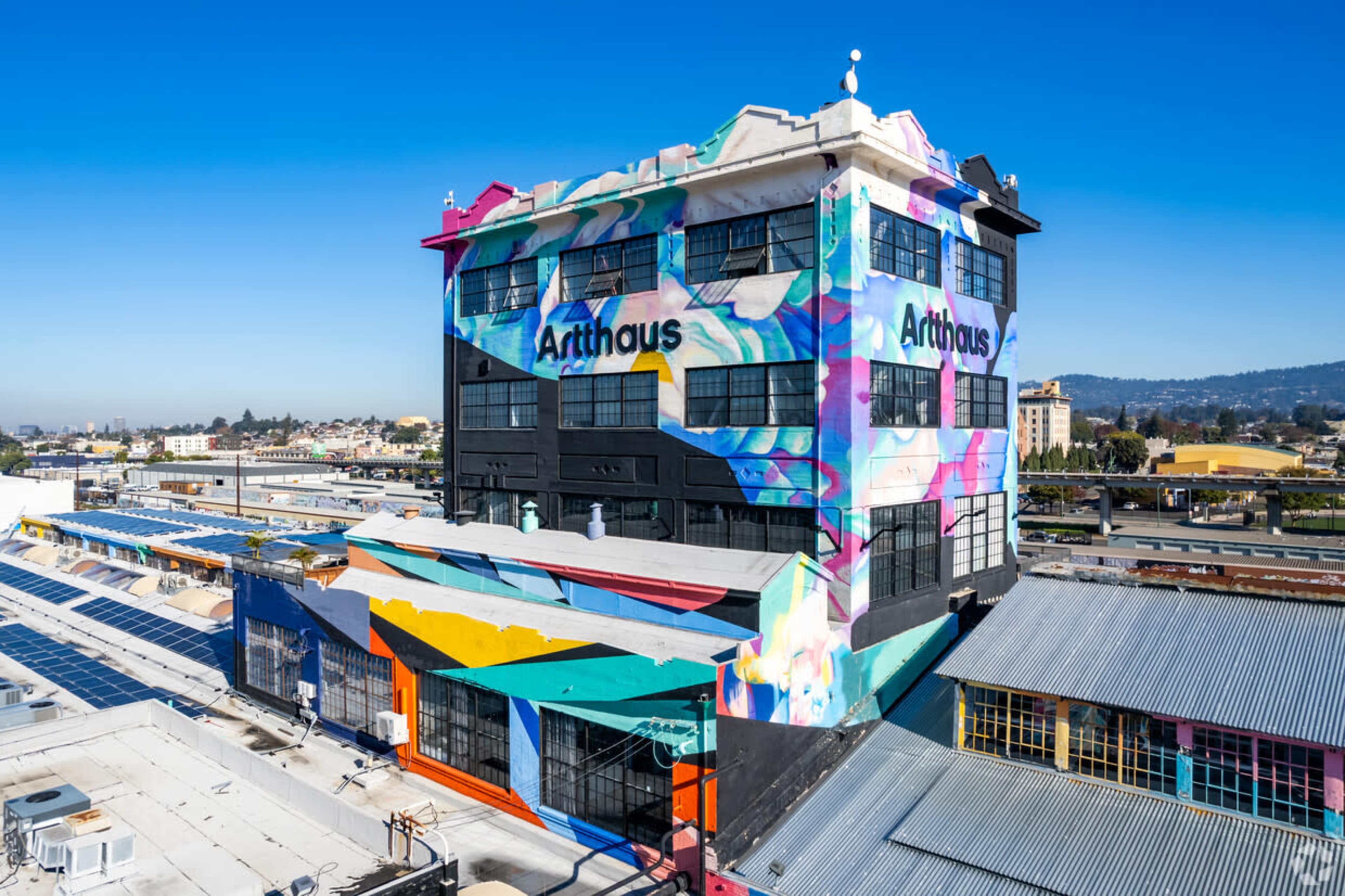 A colorful, graffiti-covered building named "Arthaus" situated in an urban area with clear blue skies in the background.
