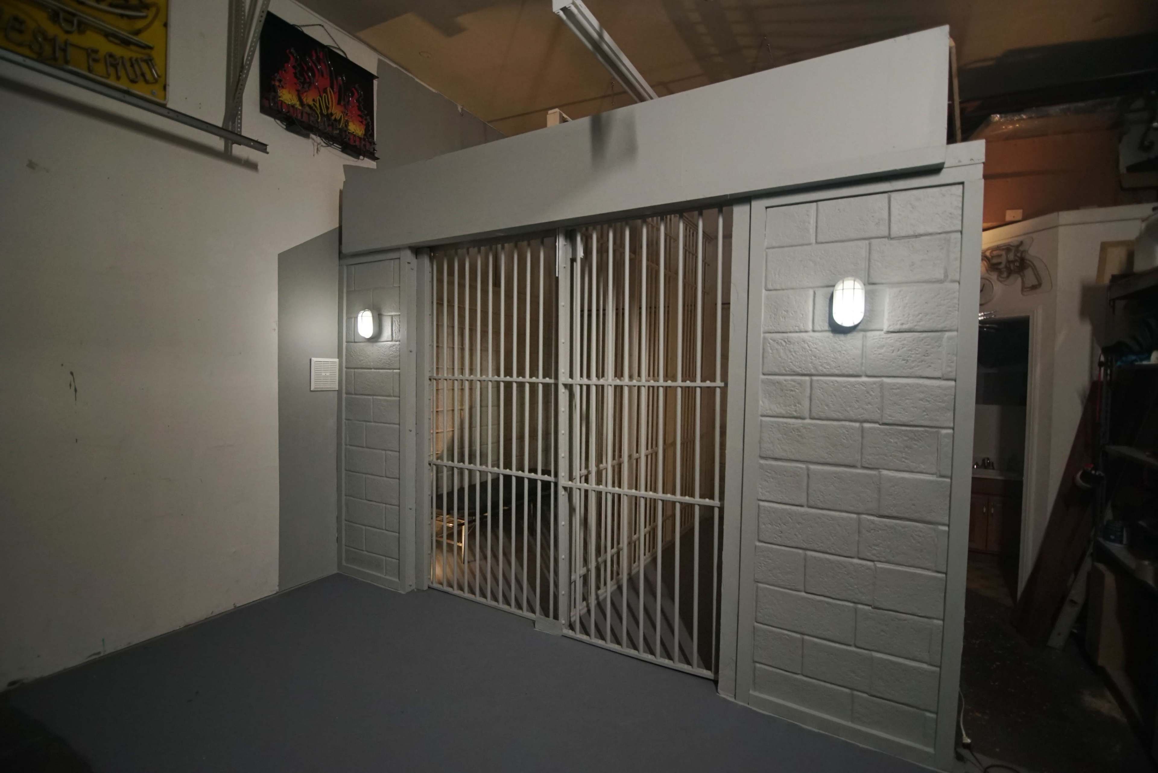 A gray cement-block wall with a barred gate and two wall-mounted lights.