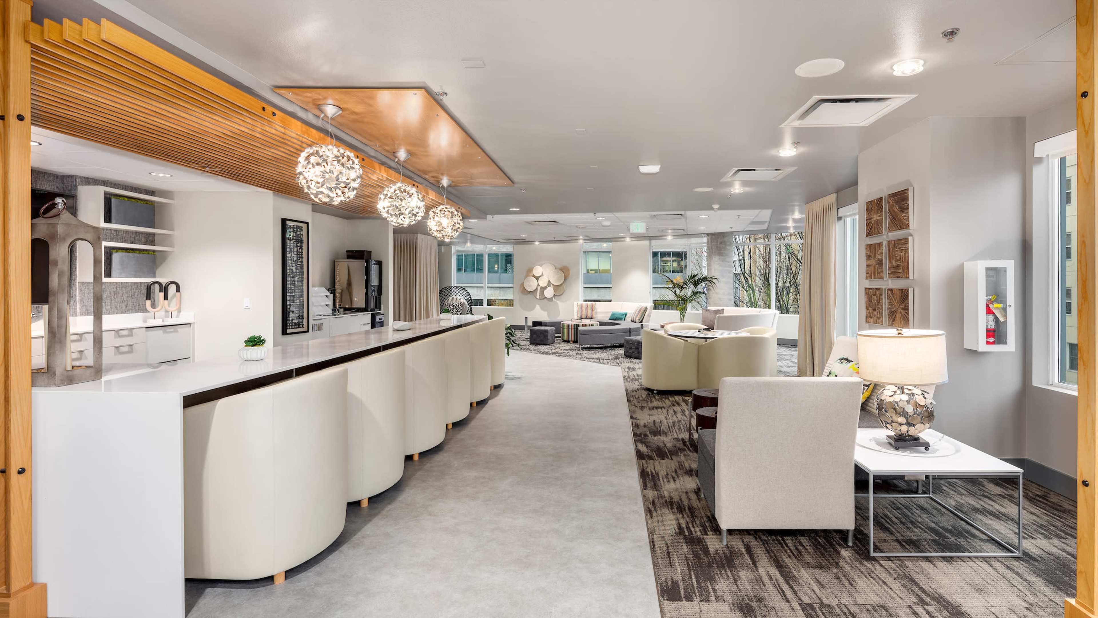 A modern lobby area features a long reception desk, comfortable seating arrangements, and decorative lighting fixtures.