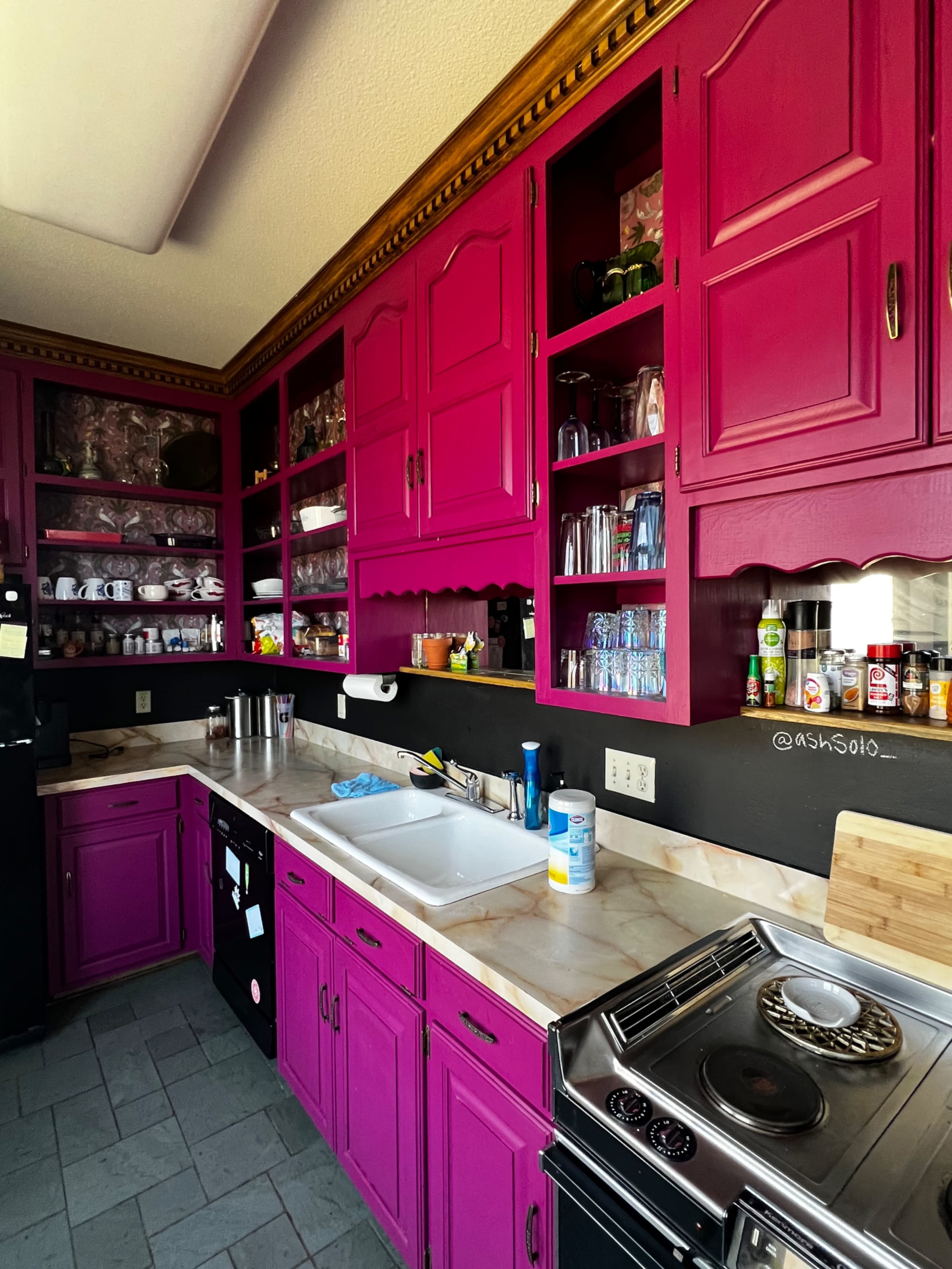 The kitchen features bright pink cabinets and a white countertop with various utensils and appliances visible.