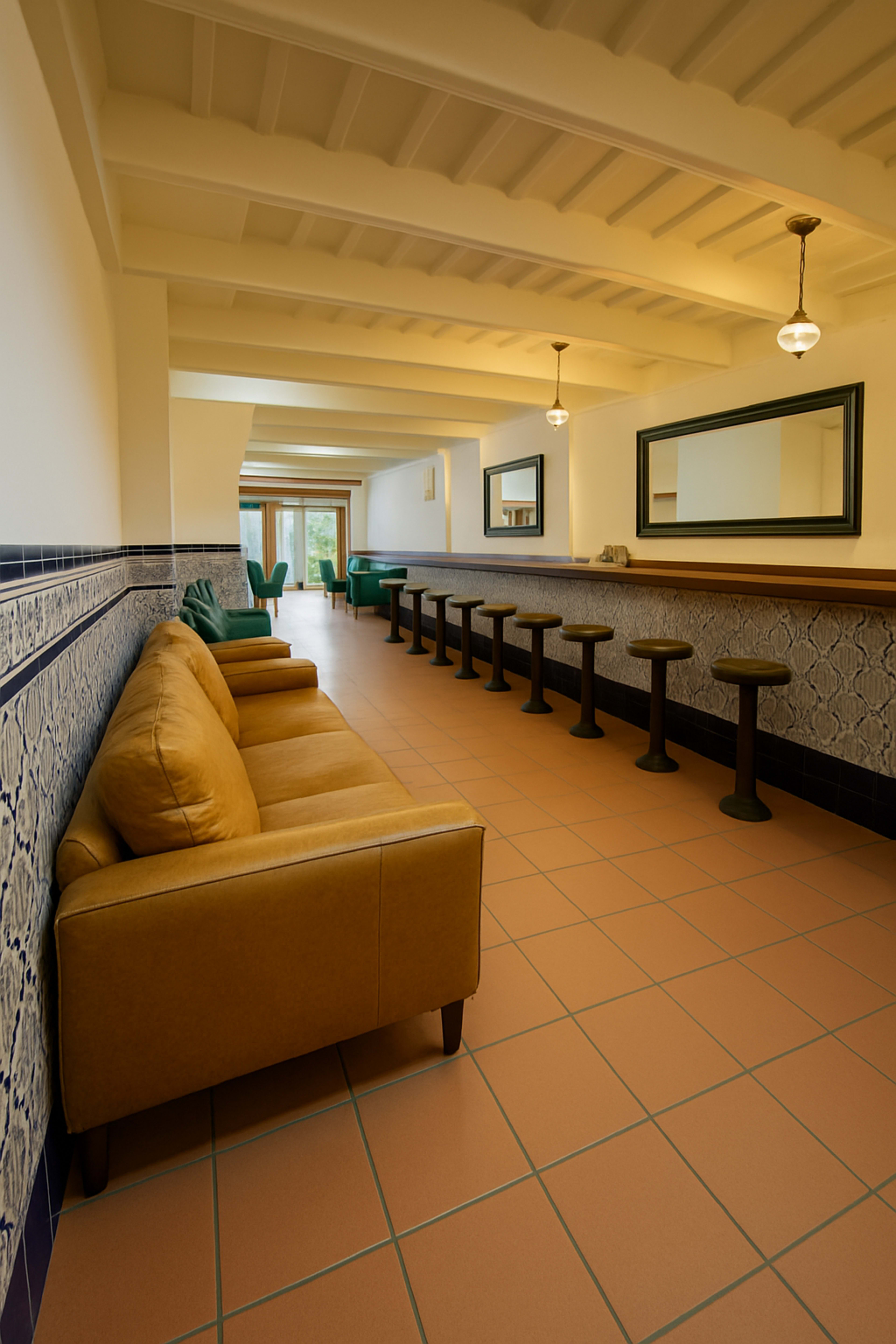 A long, narrow hallway features a tan sofa and several black bar stools against the wall, with mirrors and a pool table visible in the background.
