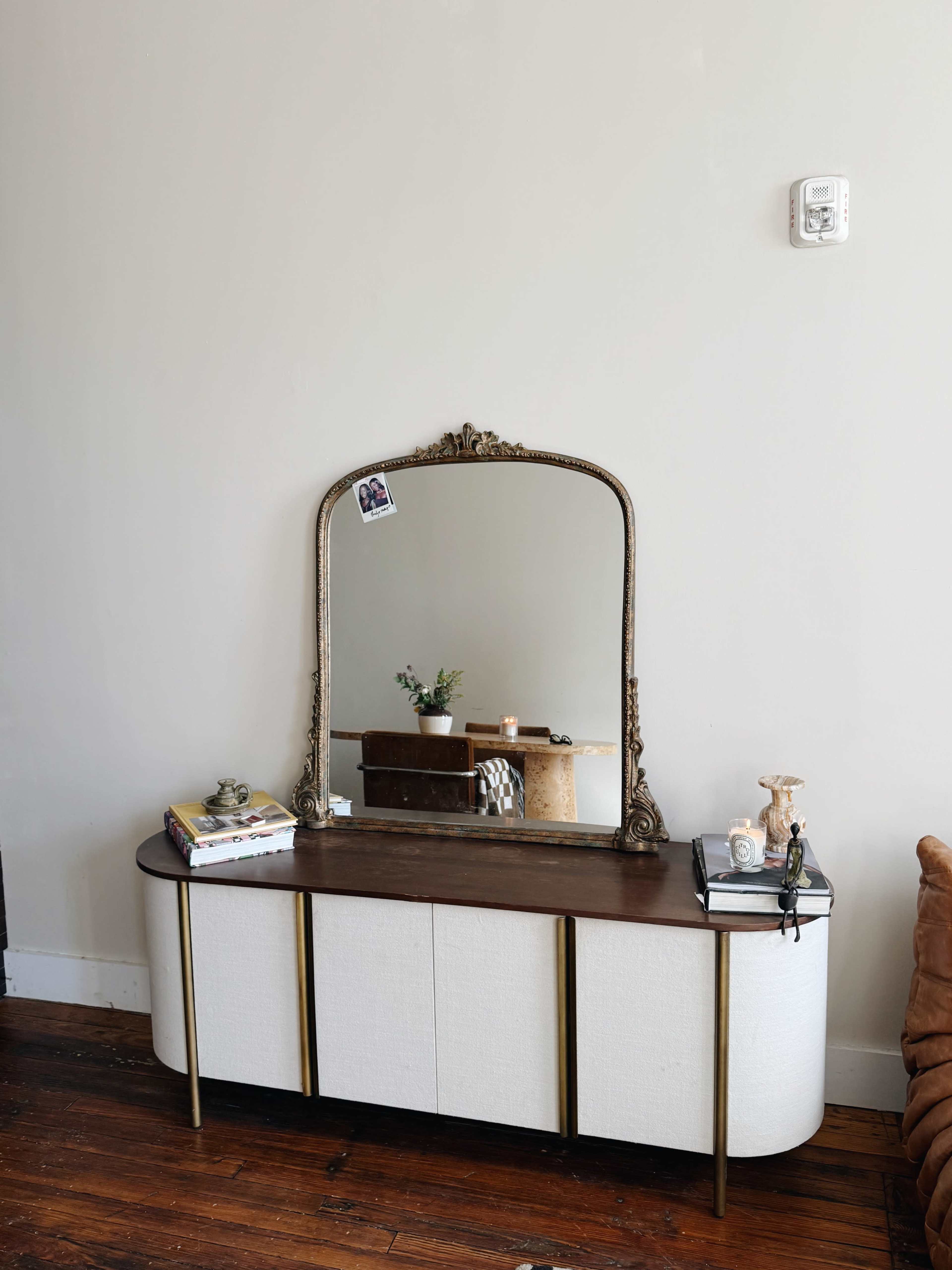 The image shows a vintage-style dresser with a large ornate mirror above it, positioned against a neutral wall.