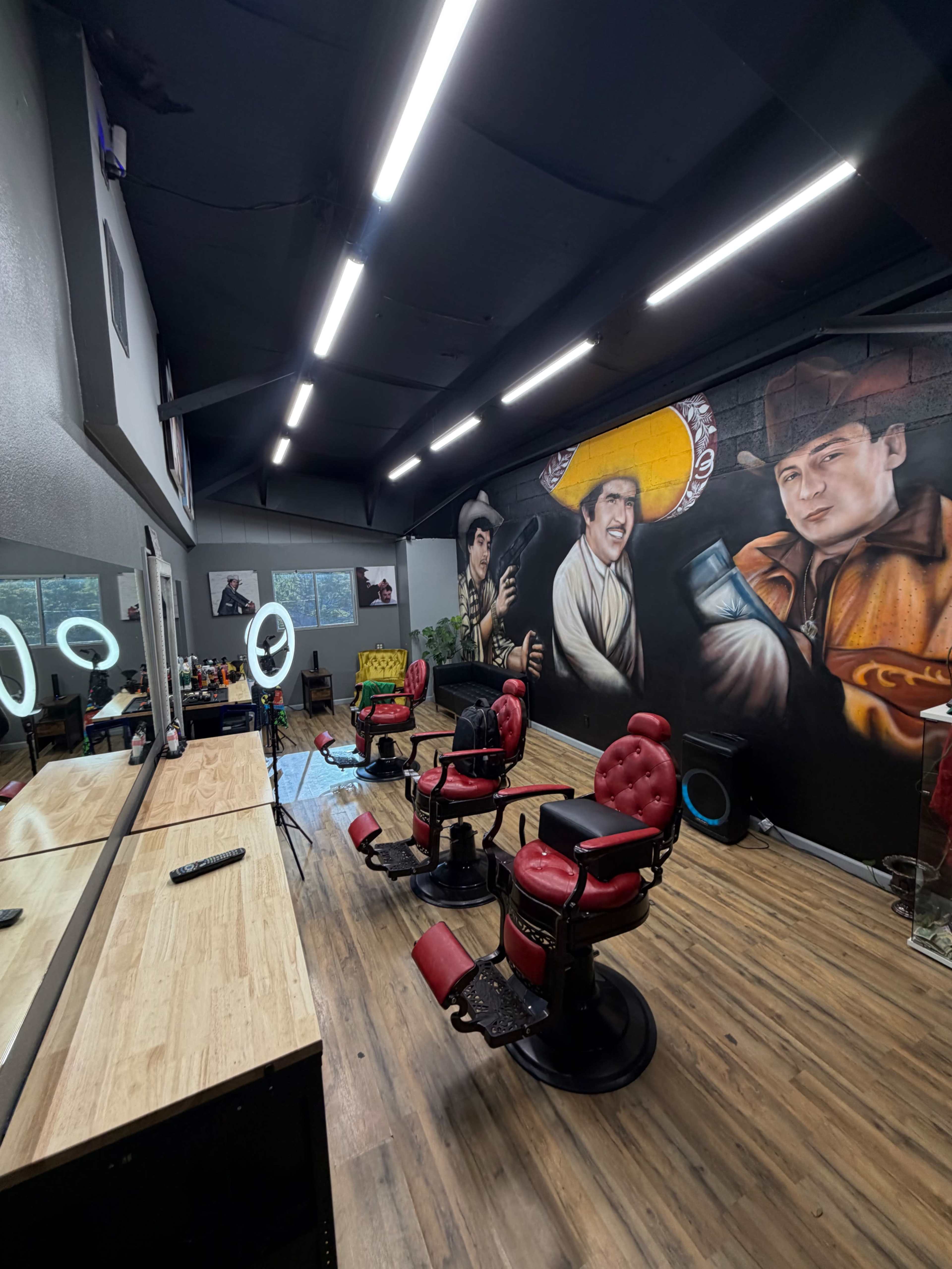 The image shows a barbershop interior with red barber chairs, mirrors, and mural artwork on the walls.