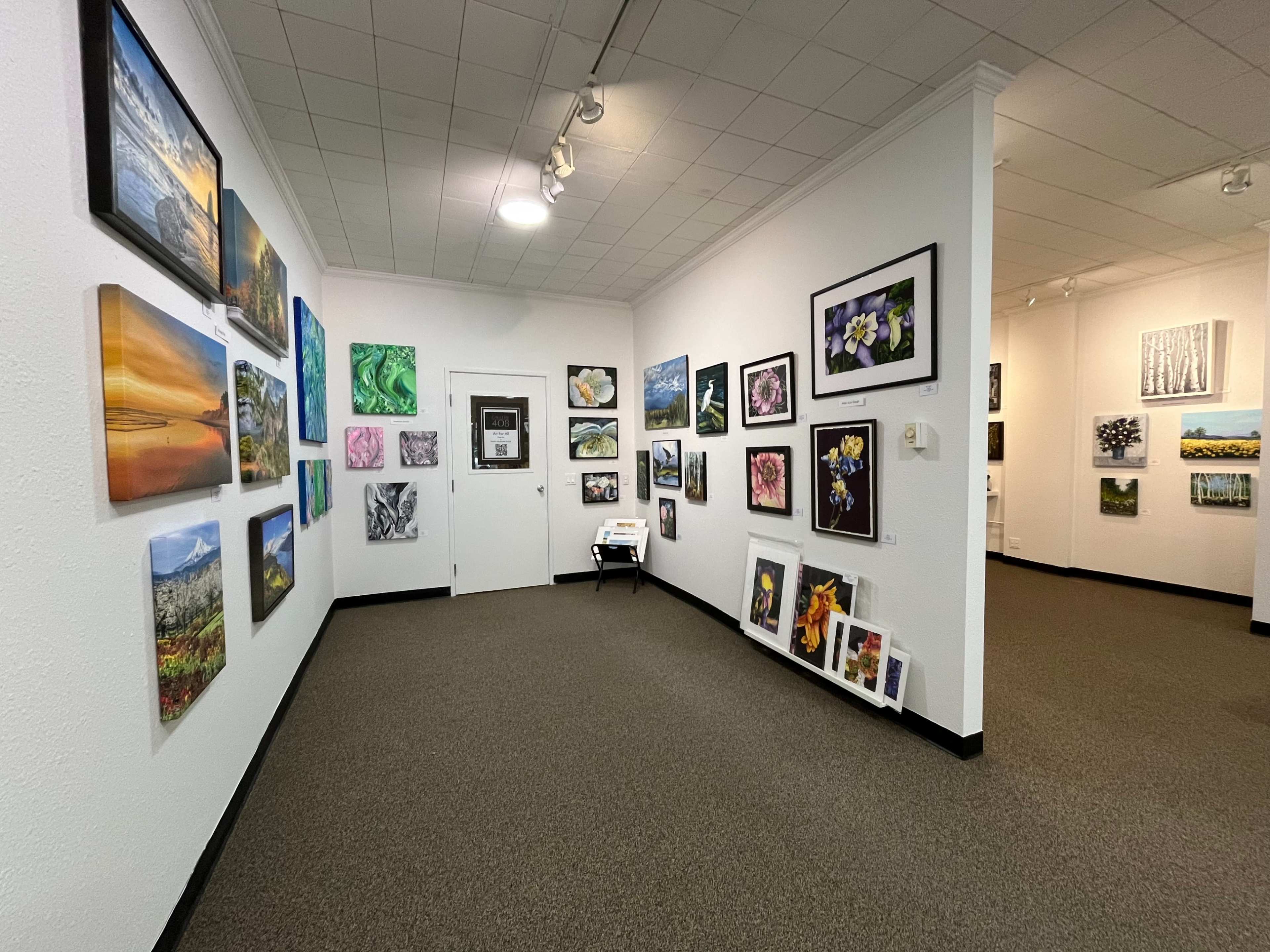 The image shows an art gallery with various paintings displayed on the walls and a doorway leading to another room.