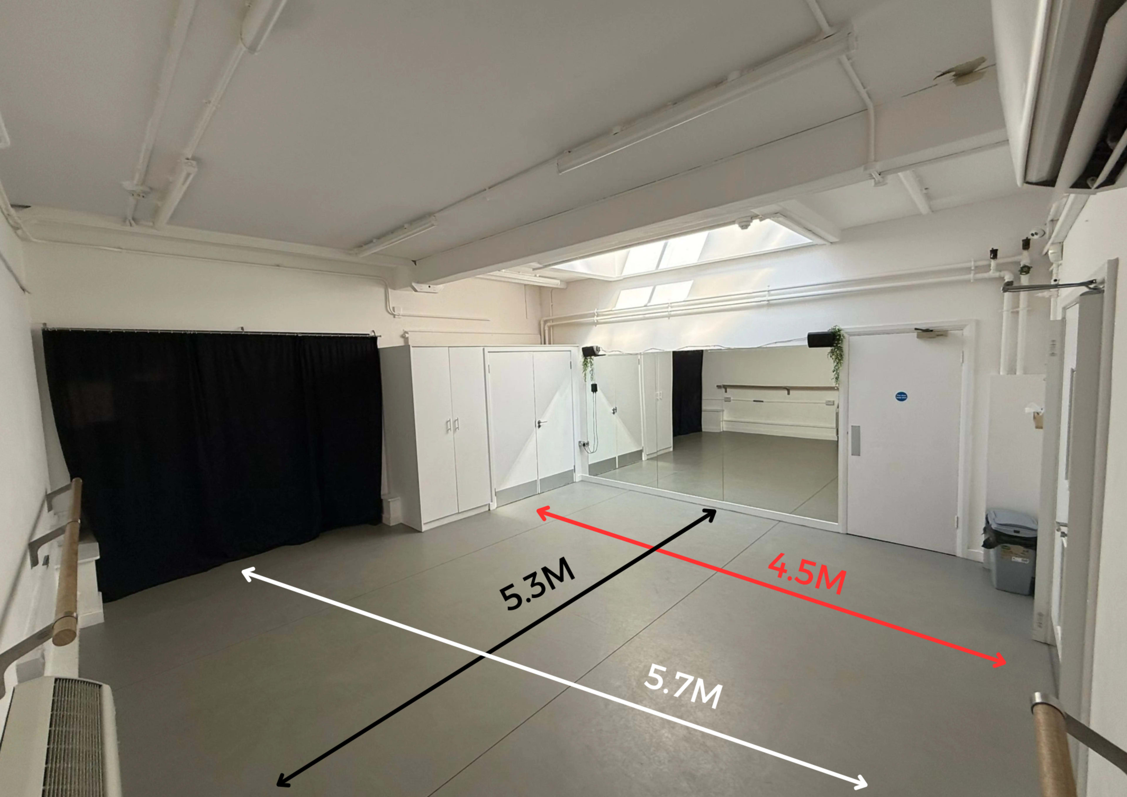 The image shows a spacious interior studio with a mirrored wall, a black curtain, and various storage cabinets.