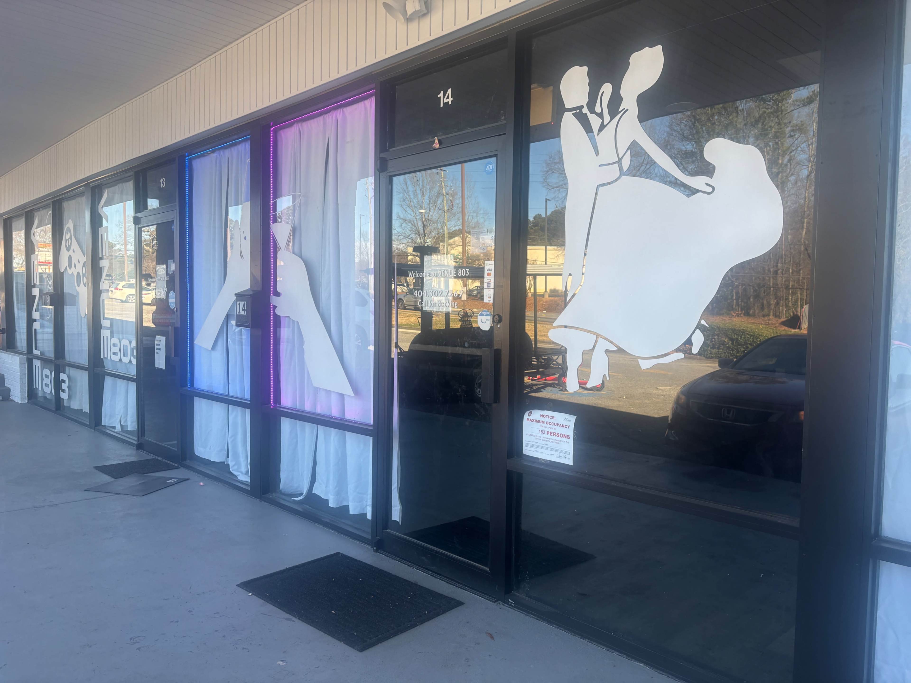 The image shows a storefront with large window displays featuring silhouettes of a couple dancing, framed by colorful curtains.