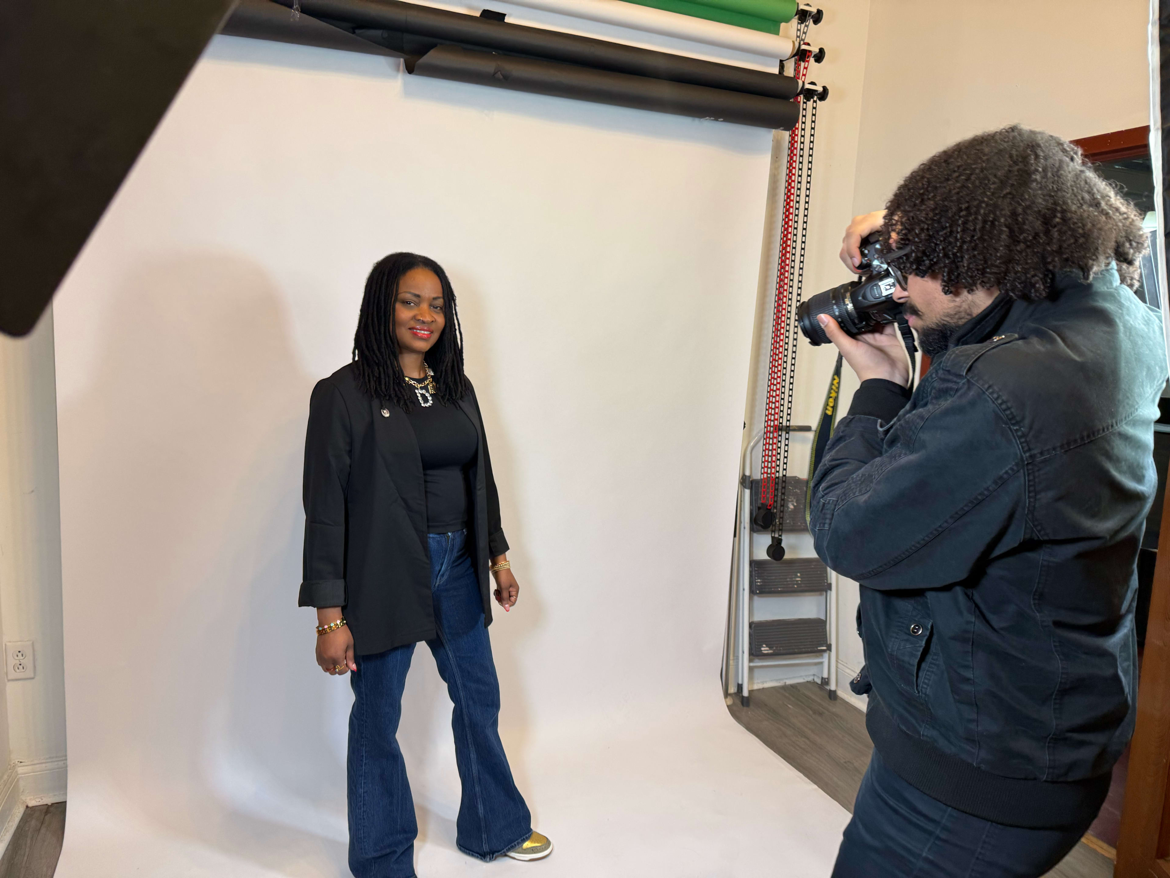 A photographer captures an individual in a studio setting against a plain backdrop.