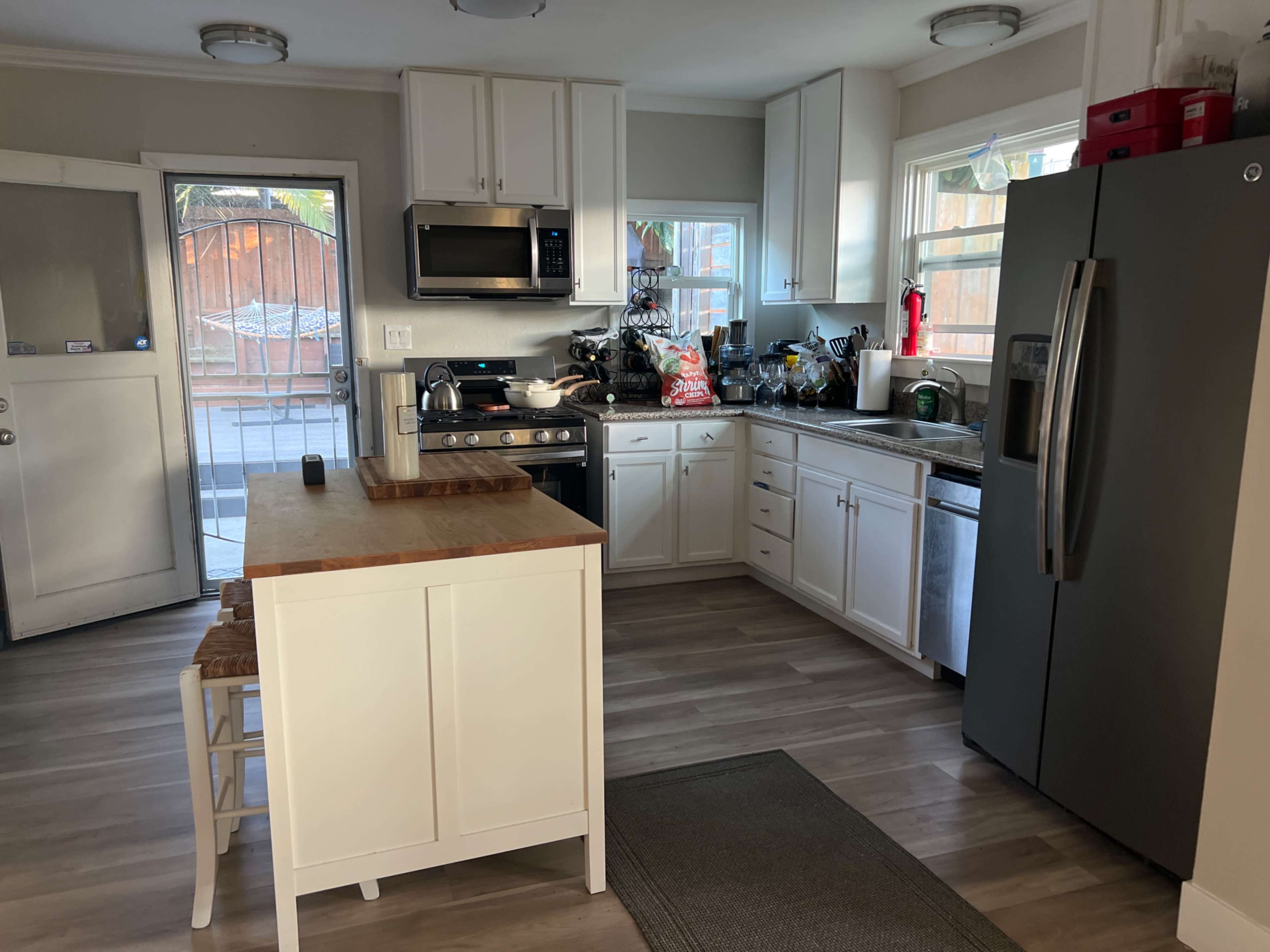 A kitchen with white cabinetry, stainless steel appliances, and a central island with a wooden countertop.