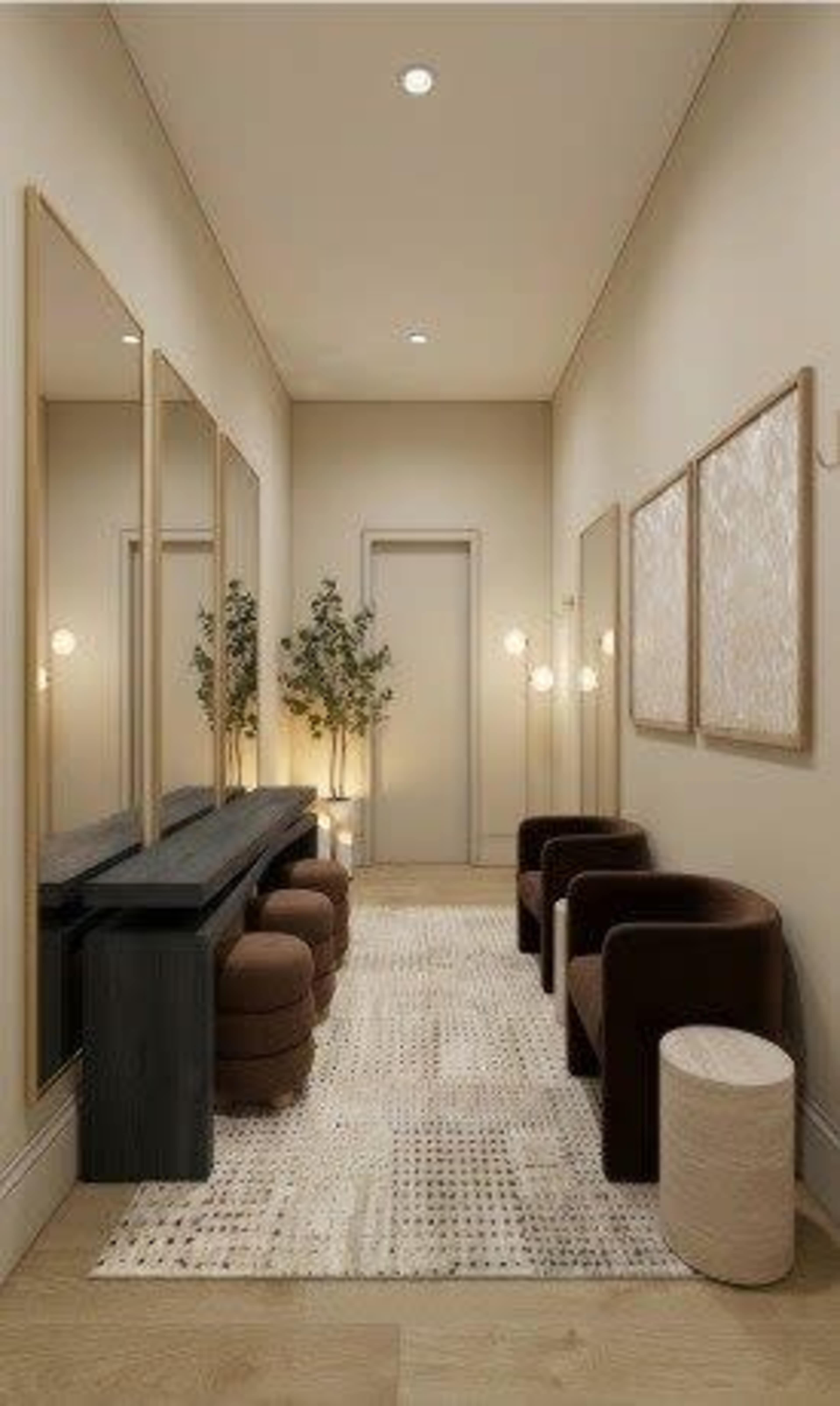 The image shows a neatly designed hallway featuring three large mirrors, two brown chairs, a small round table, and decorative plants, with soft lighting illuminating the space.