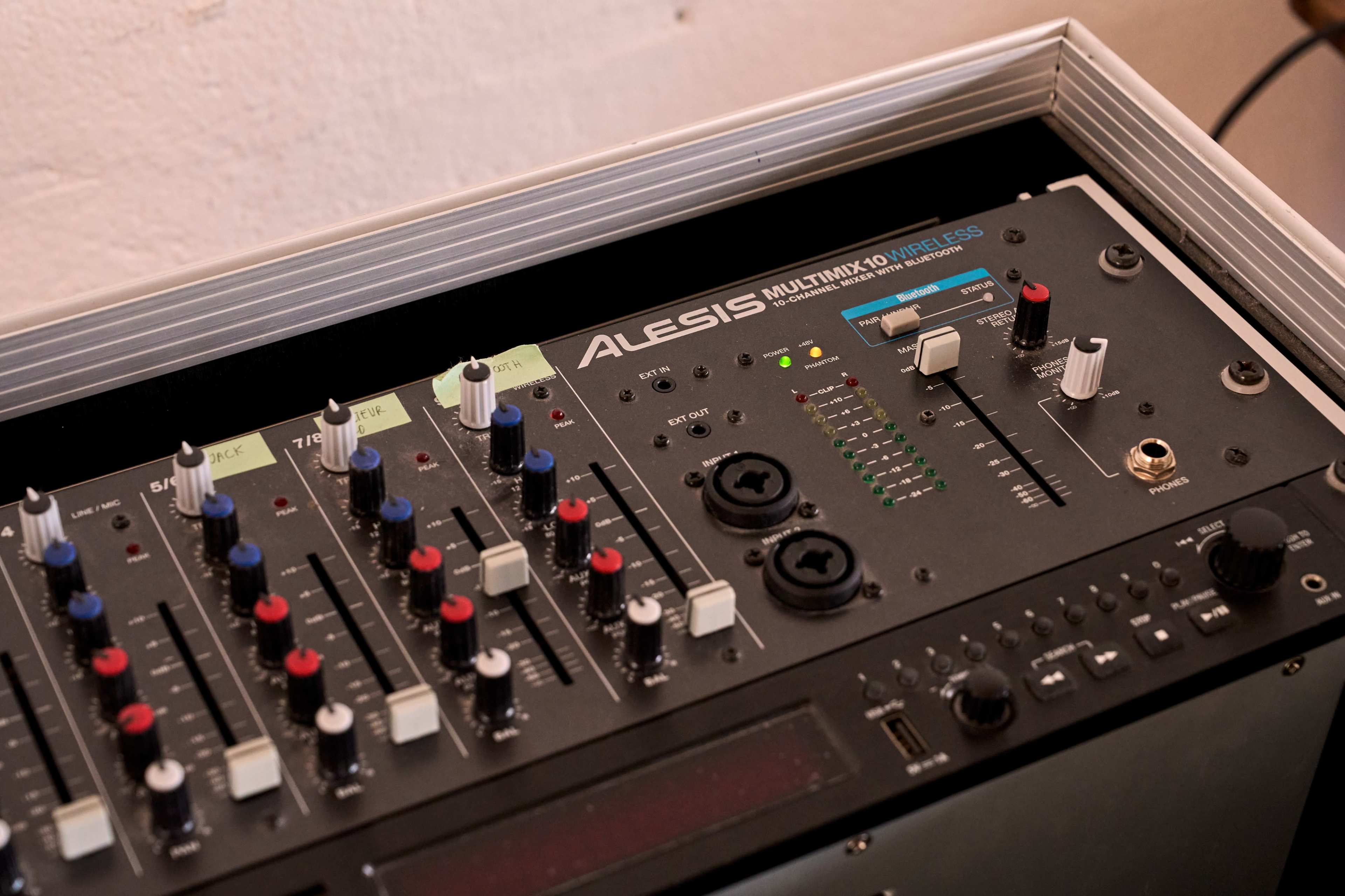 The image shows an Alesis Multimix 10 audio mixer with various knobs and sliders on its surface.