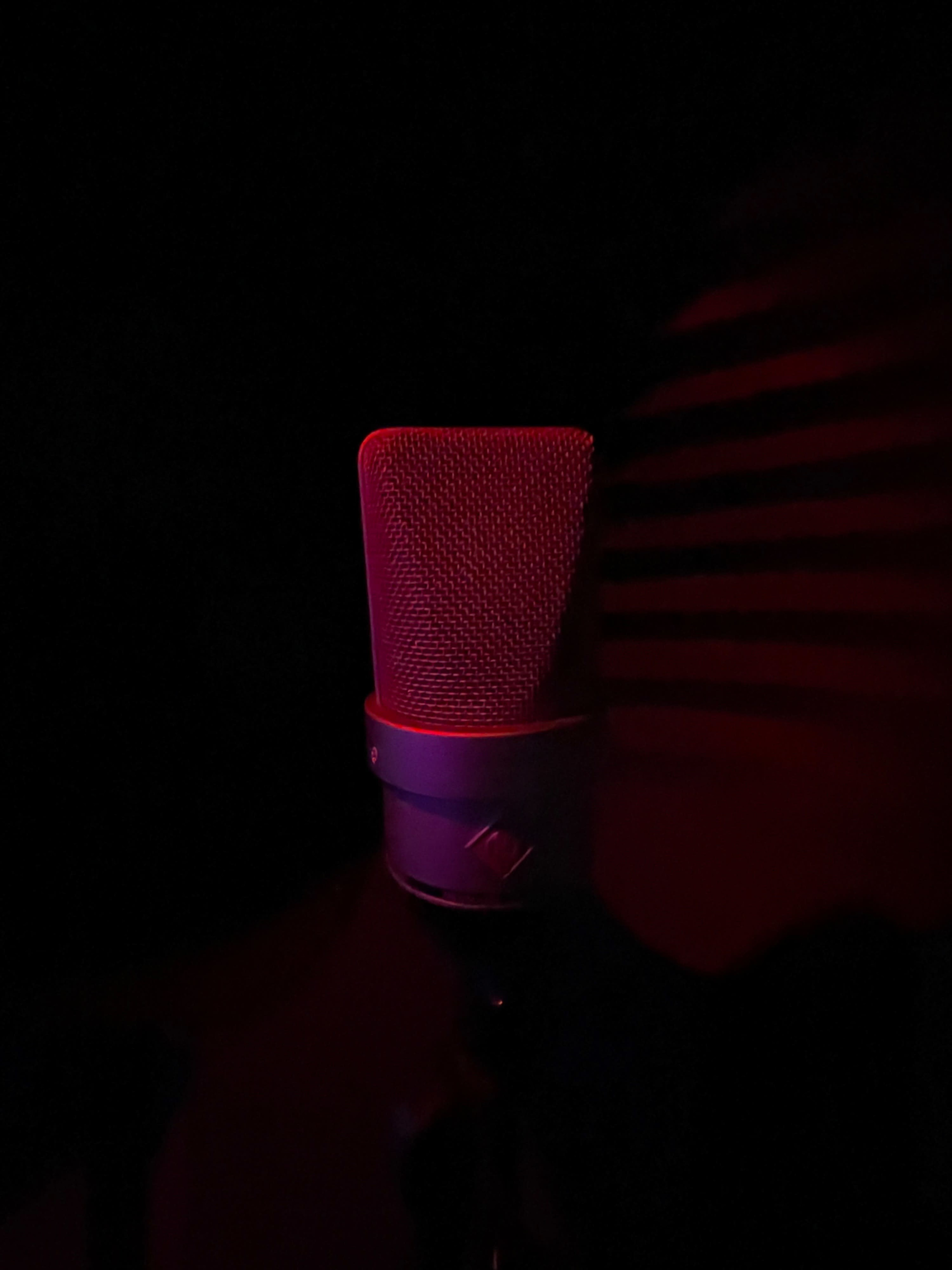 A microphone with a red glow is positioned in a dimly lit environment.