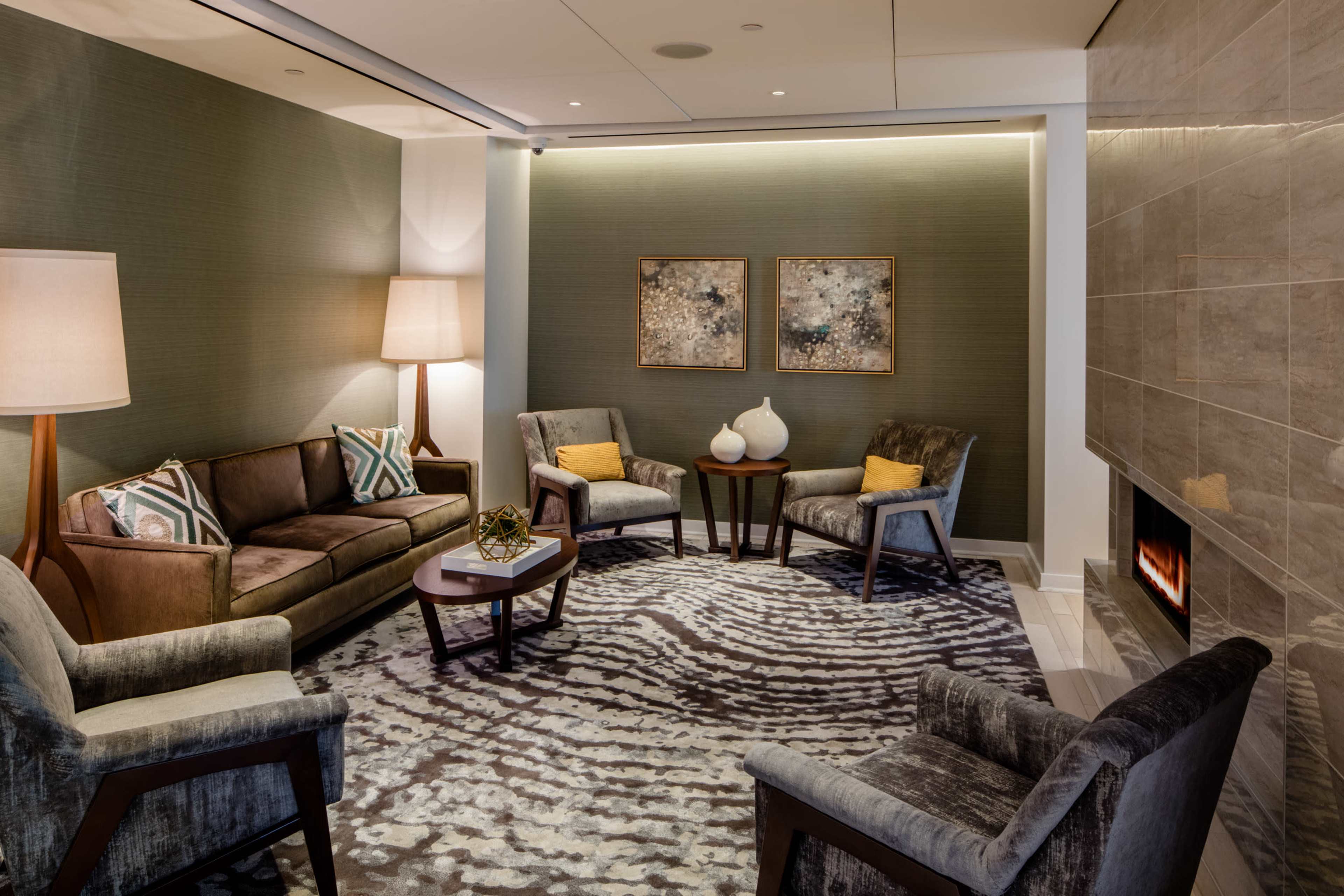 A stylish seating area features a sofa and chairs arranged around a small table, with art on the walls and a fireplace nearby.