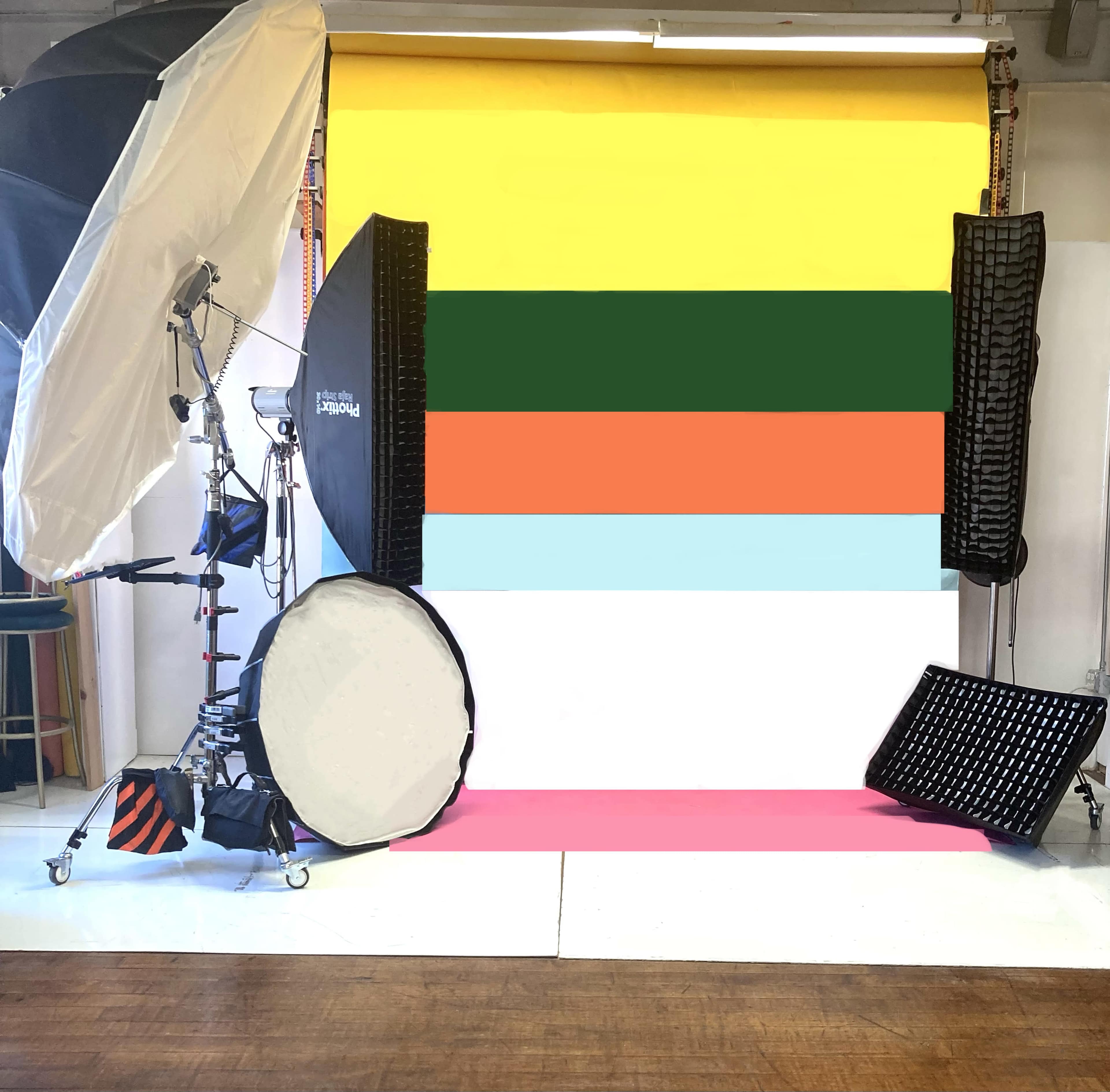 A photography studio setup with a colorful backdrop and various lighting equipment arranged around it.